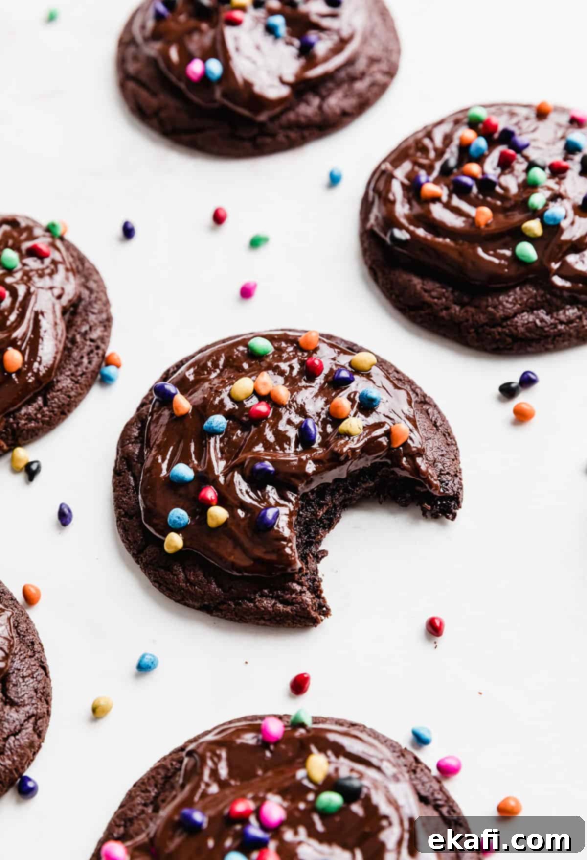 Κραμπλ Ουράνια Μπισκότα Μπράουνι 10 Ένα Crumbl Cosmic Brownie μπισκότο με επικάλυψη σοκολατένιας γκανάζ και πολύχρωμα ζαχαρωτά σε λευκό φόντο, έτοιμο για σερβίρισμα.