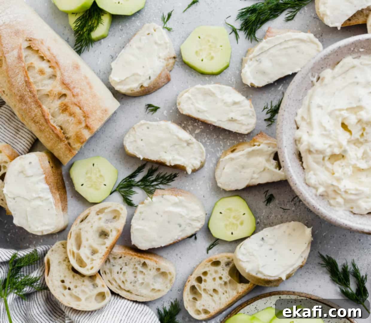 Cool Cucumber Cream Cheese Poppers 7 Ranch cream cheese mixture smeared atop sliced baguettes, with cucumbers in the background.