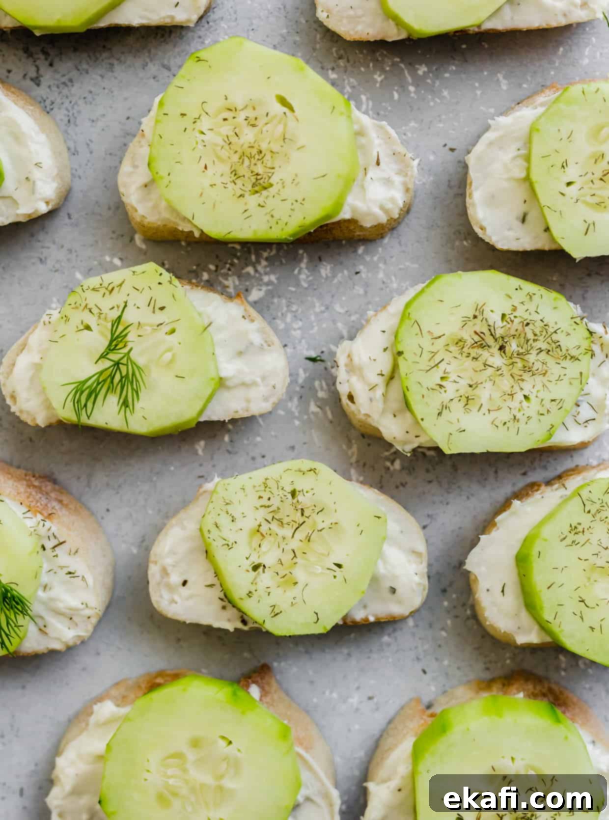 Cool Cucumber Cream Cheese Poppers 8 A collection of sliced cucumbers atop a cream cheese mixture on a sliced baguette.