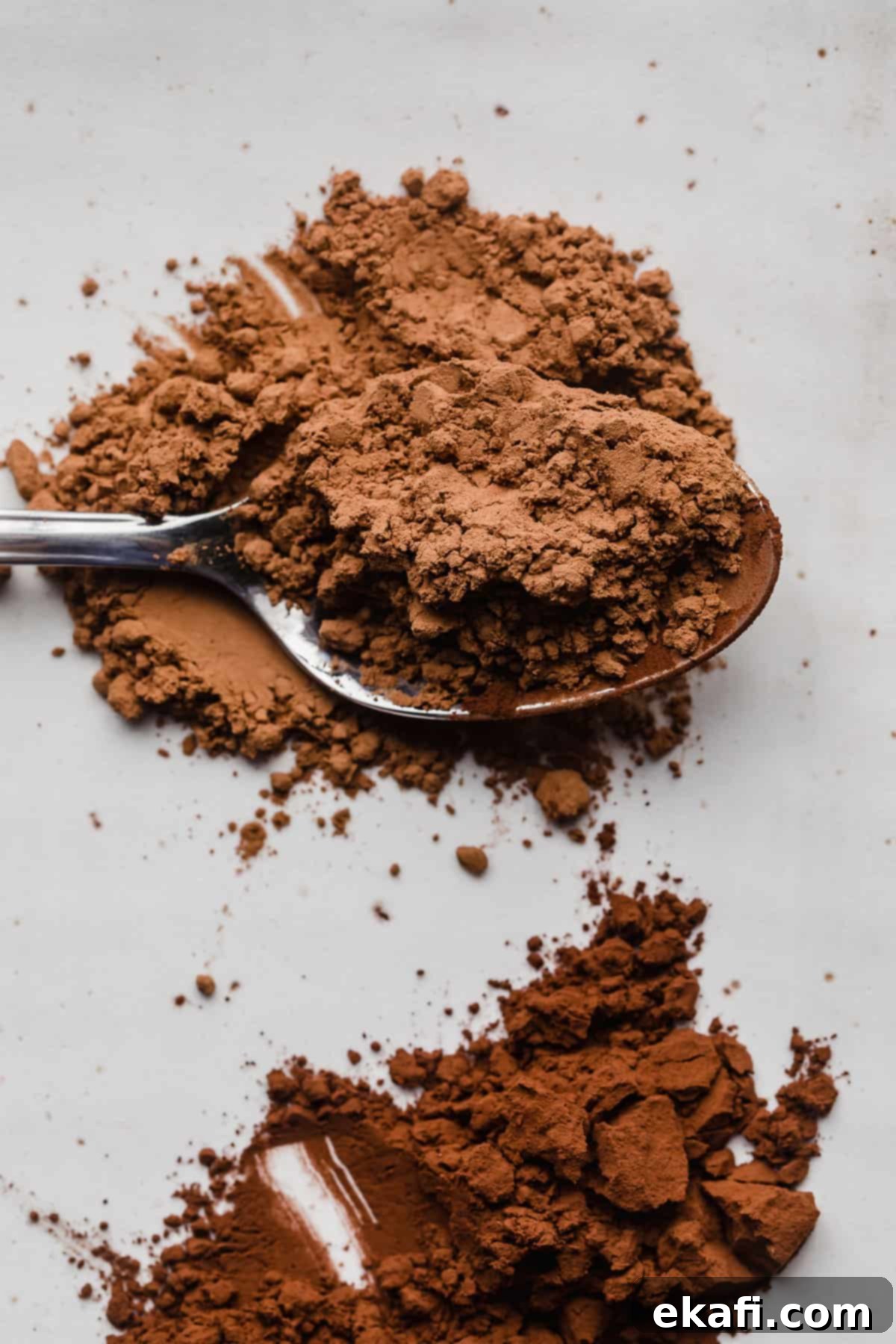 The Ultimate Guide to Baking Cocoa 3 A close-up shot of a spoon overflowing with light brown unsweetened cocoa powder, highlighting its fine texture and classic color.