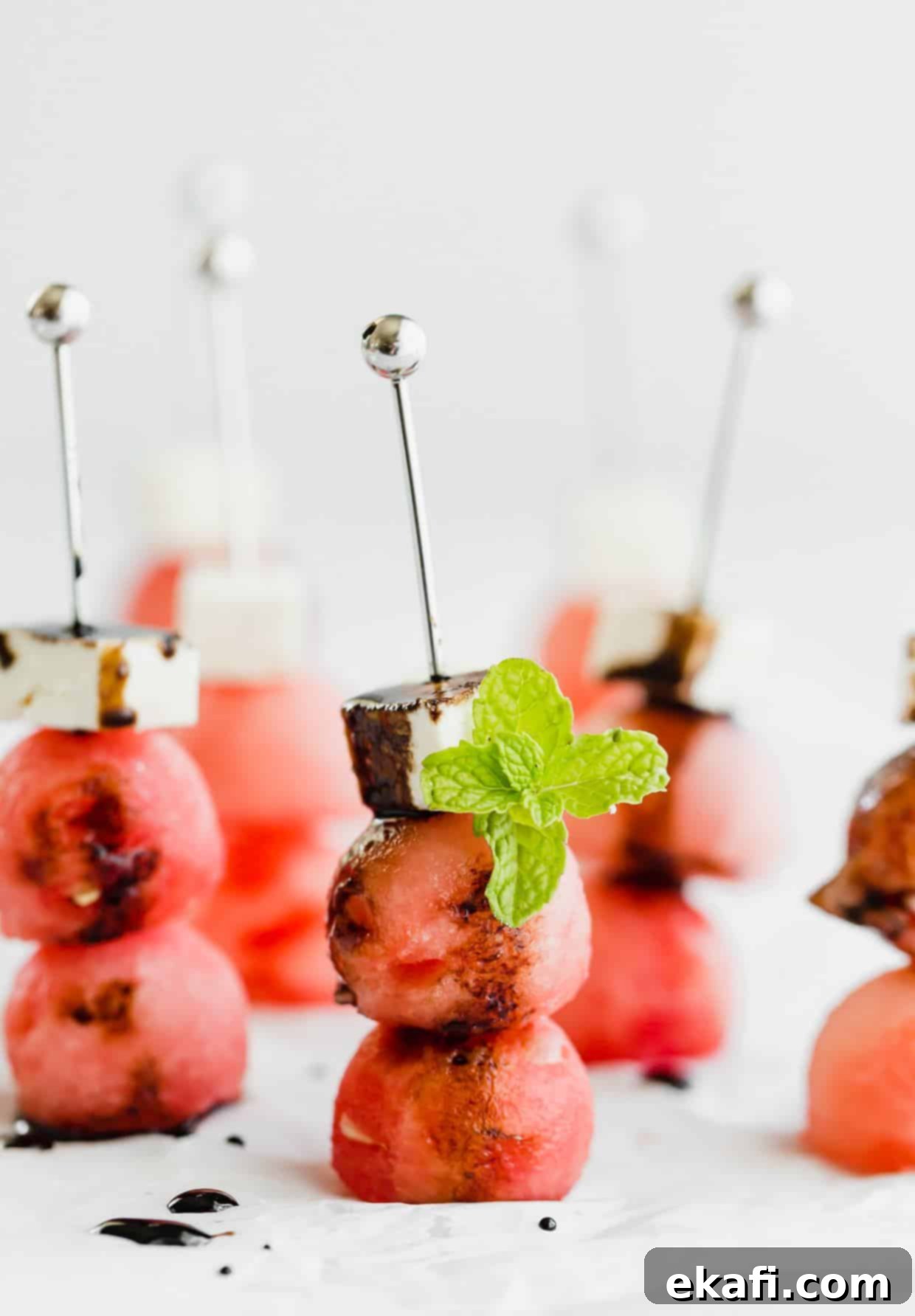 Cool Watermelon Sticks 2 Two watermelon balls and a block of feta on small skewers, drizzled with balsamic reduction and a mint leaf for garnish. A perfect light and refreshing summer appetizer.