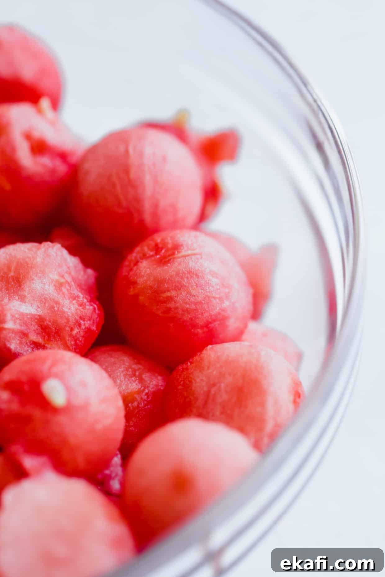 Cool Watermelon Sticks 4 A close-up photo of freshly scooped, round watermelon balls in a clear glass bowl, glistening with juice.