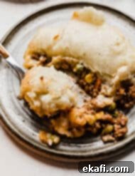 Hearty Lamb Potato Casserole 18 A slice of Shepherd's Pie with rosemary, corn, and peas visible in the rich ground beef mixture beneath the golden mashed potato topping.