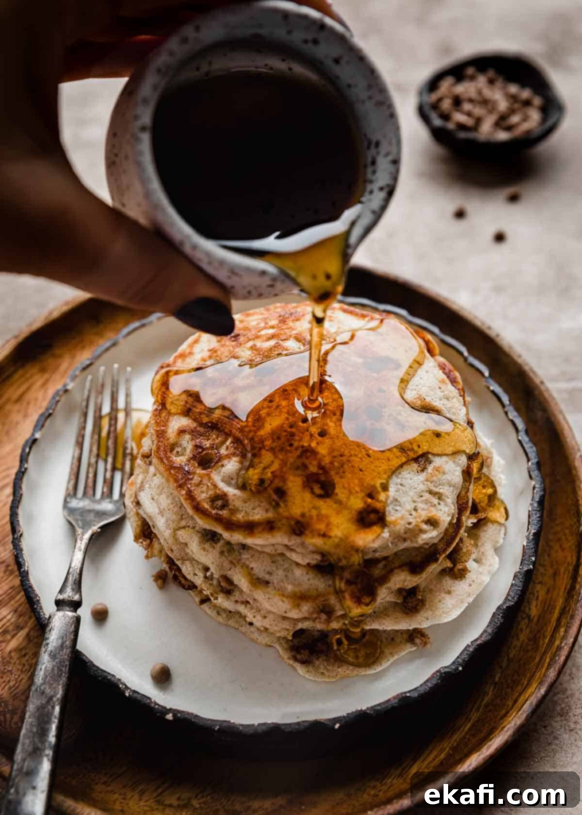 Irresistible Cinnamon Chip Pancakes 6 Maple syrup being poured overtop a stack of Cinnamon Chip Pancakes.