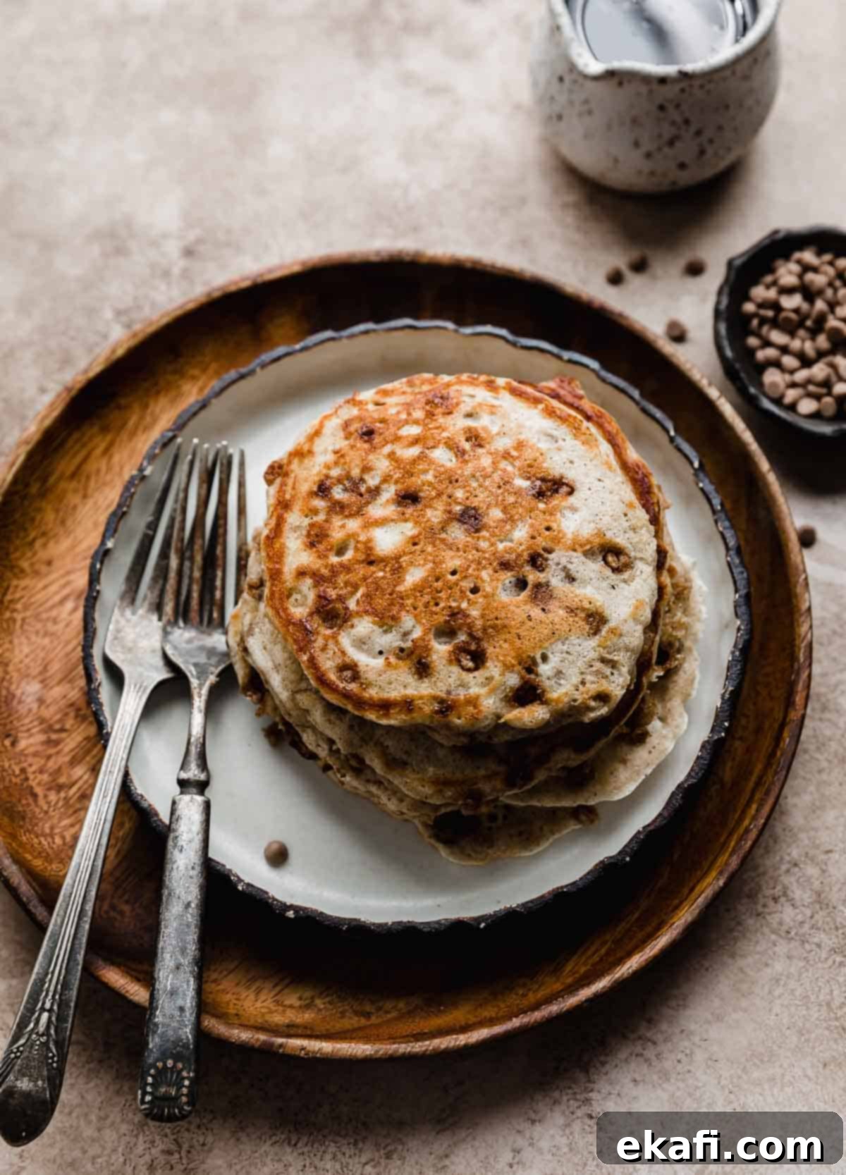 Irresistible Cinnamon Chip Pancakes 7 A stack of four Cinnamon Chip Pancakes on a brown wooden plate.