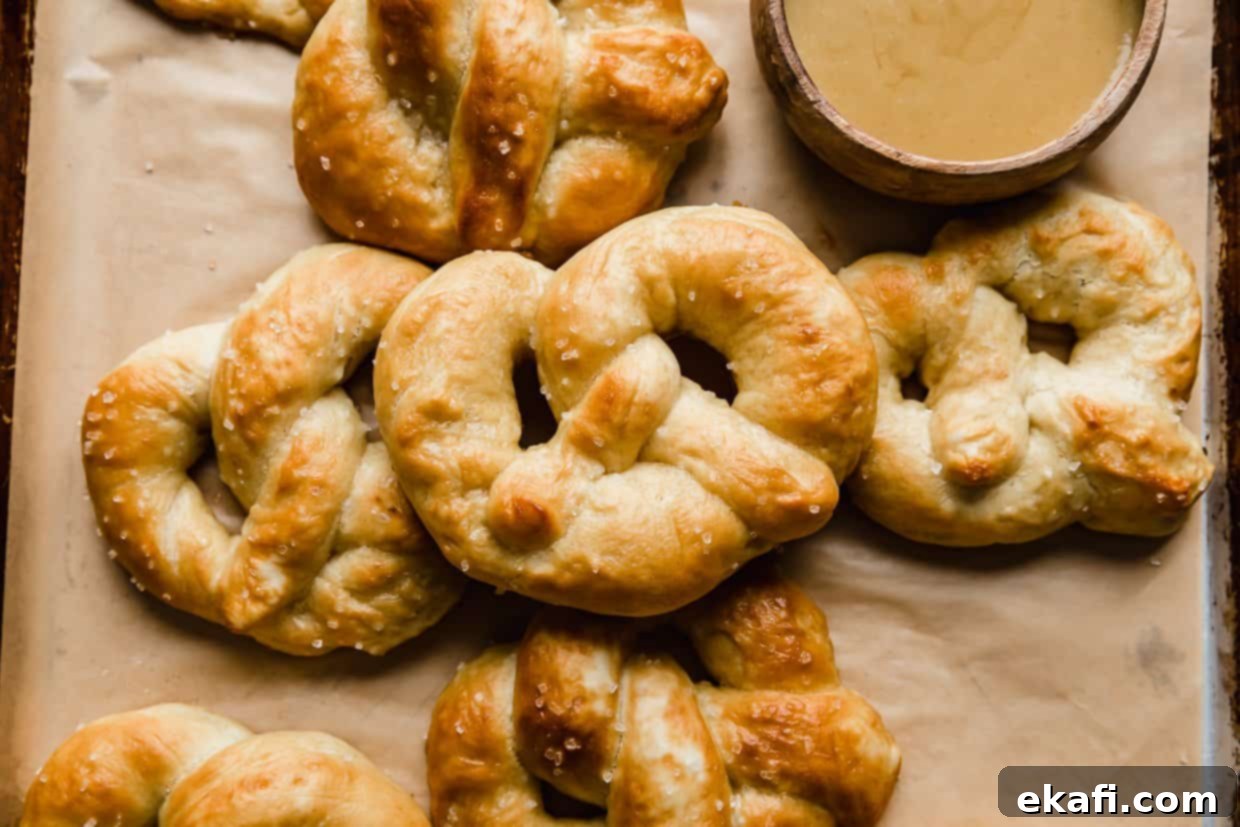 Perfect Homemade Soft Pretzels 12 A close-up of several Homemade Soft Pretzels artfully arranged on tan parchment paper, highlighting their golden crust and coarse salt.