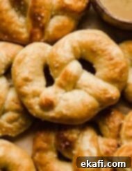 Perfect Homemade Soft Pretzels 13 Golden baked Homemade Pretzels on a tan background, perfect for a snack or party appetizer.