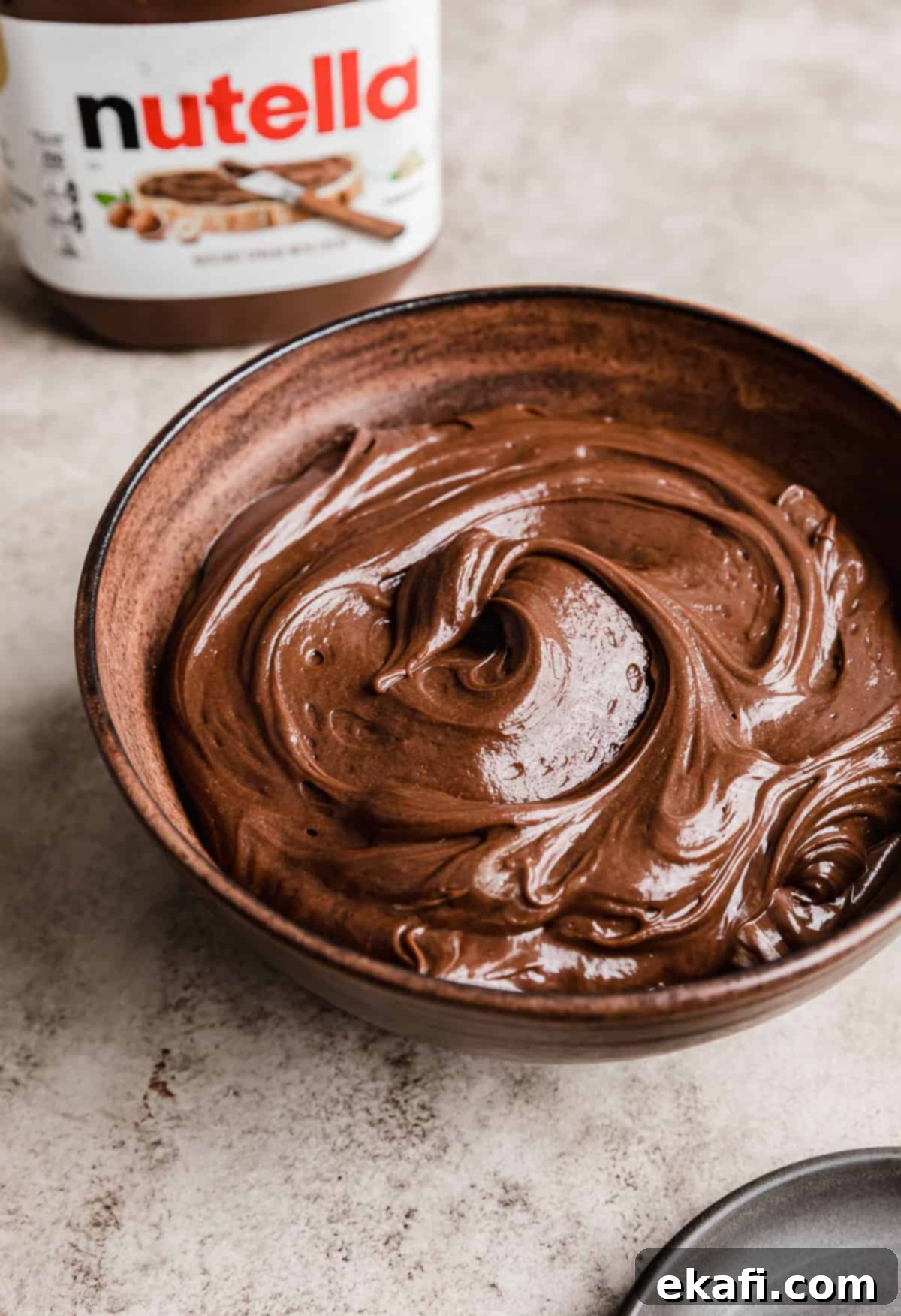Σαντιγί Νουτέλλας 7 Σαντιγί Nutella σε ένα καφέ μπολ με ένα βάζο Nutella στο φόντο.
