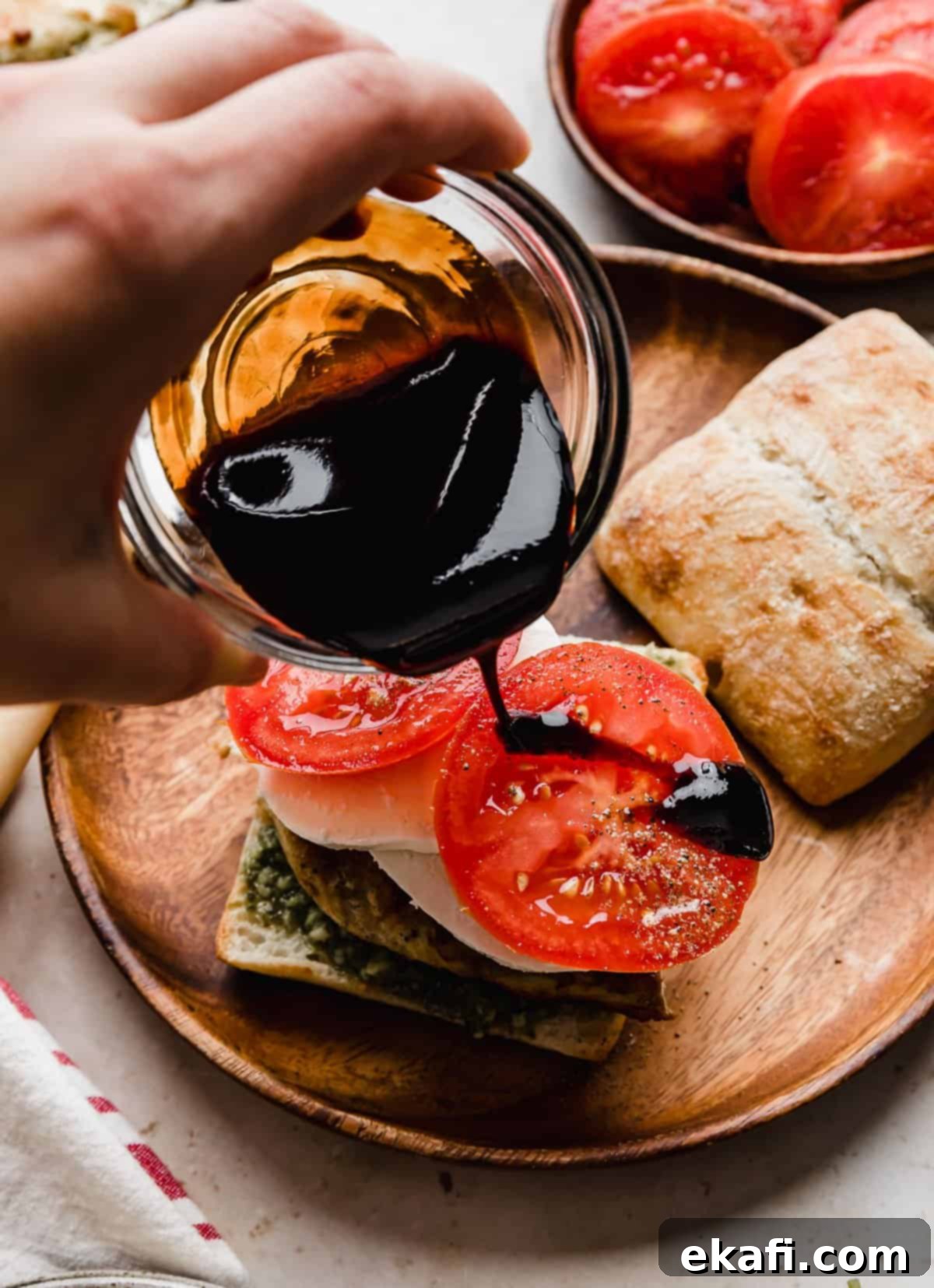 Σάντουιτς Κοτόπουλο Καπρέζε 8 Βαλσαμική κρέμα περιχύνεται πάνω από φέτες ντομάτας σε ένα Κοτόπουλο Καπρέζε Σάντουιτς.