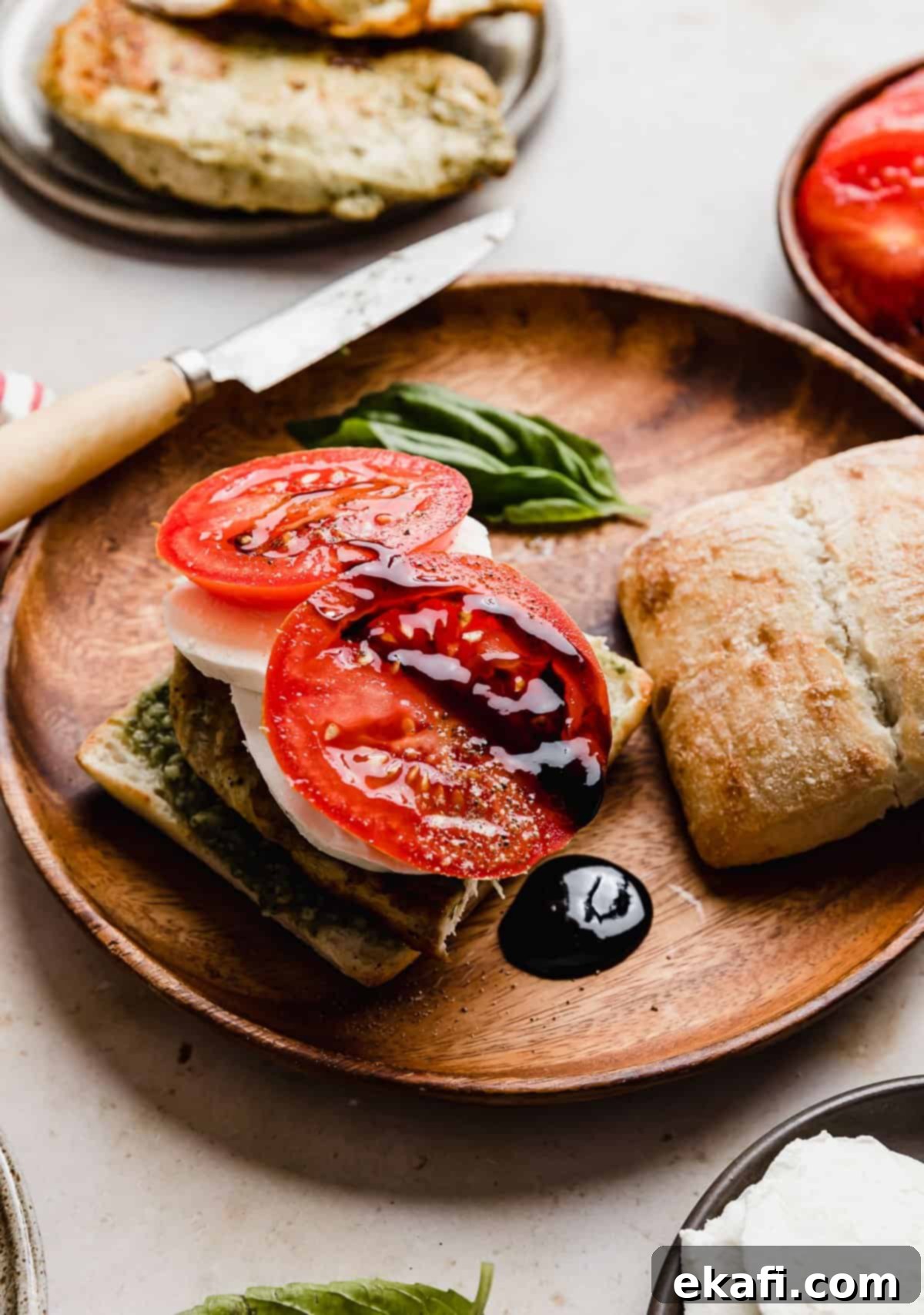 Σάντουιτς Κοτόπουλο Καπρέζε 9 Βαλσαμική κρέμα που στάζει από μια φρέσκια ντομάτα σε ένα Κοτόπουλο Καπρέζε Σάντουιτς σε χειροποίητο ψωμί.