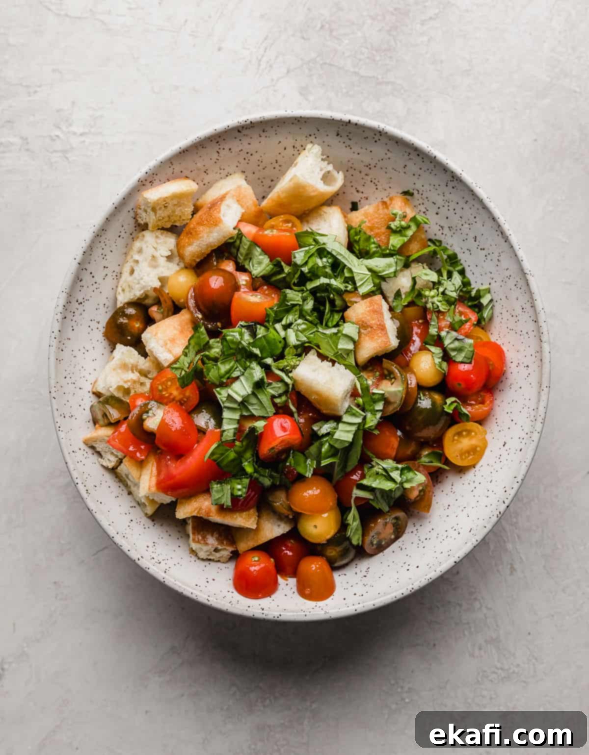 Rustic Tuscan Panzanella 7 A large bowl with stale bread, chopped tomatoes, and chopped basil in it.