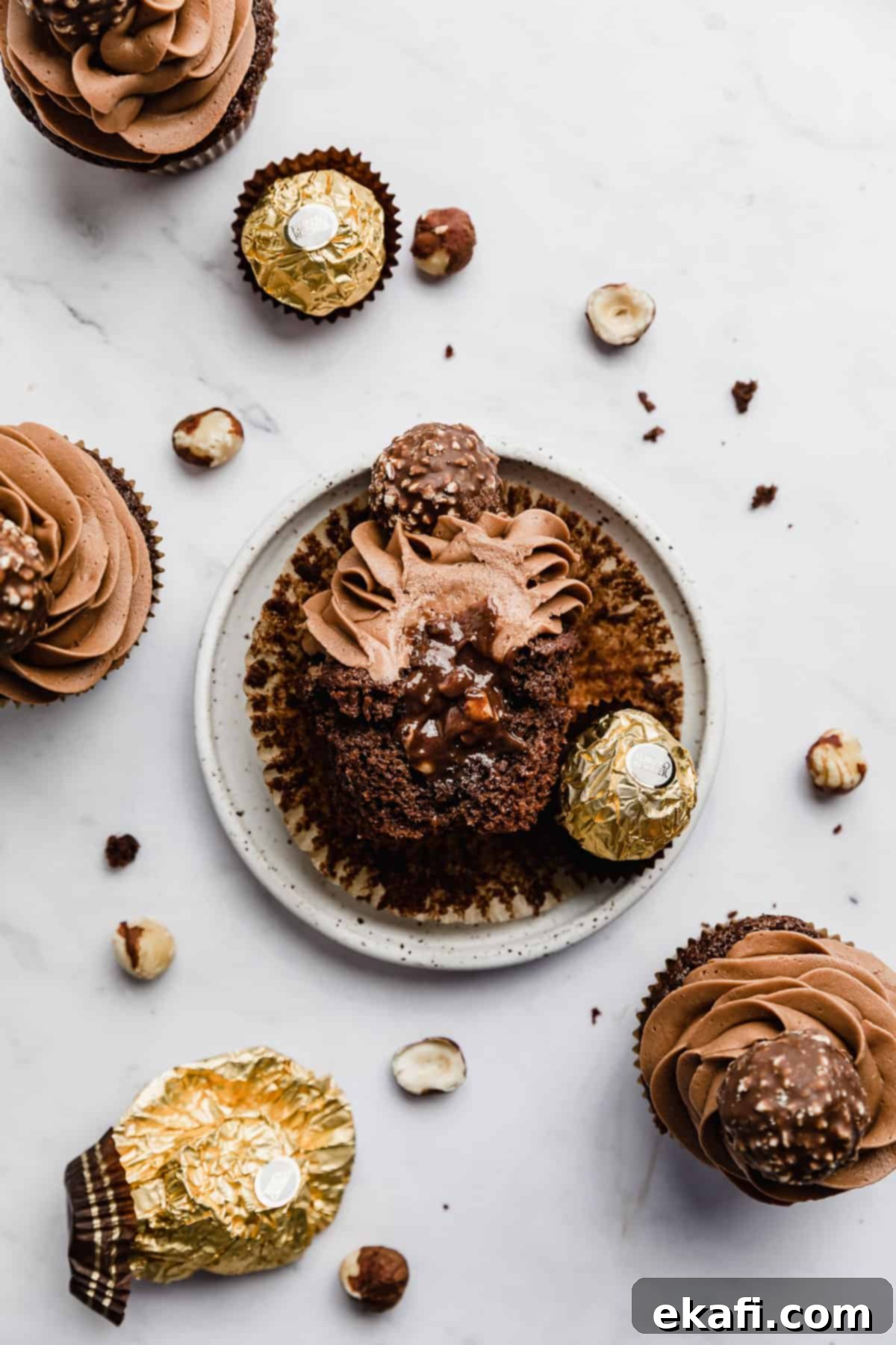 Decadent Ferrero Rocher Cupcakes 12 Half of a Ferrero Rocher Cupcake on a white plate with Nutella spilling from the center of the cupcake.