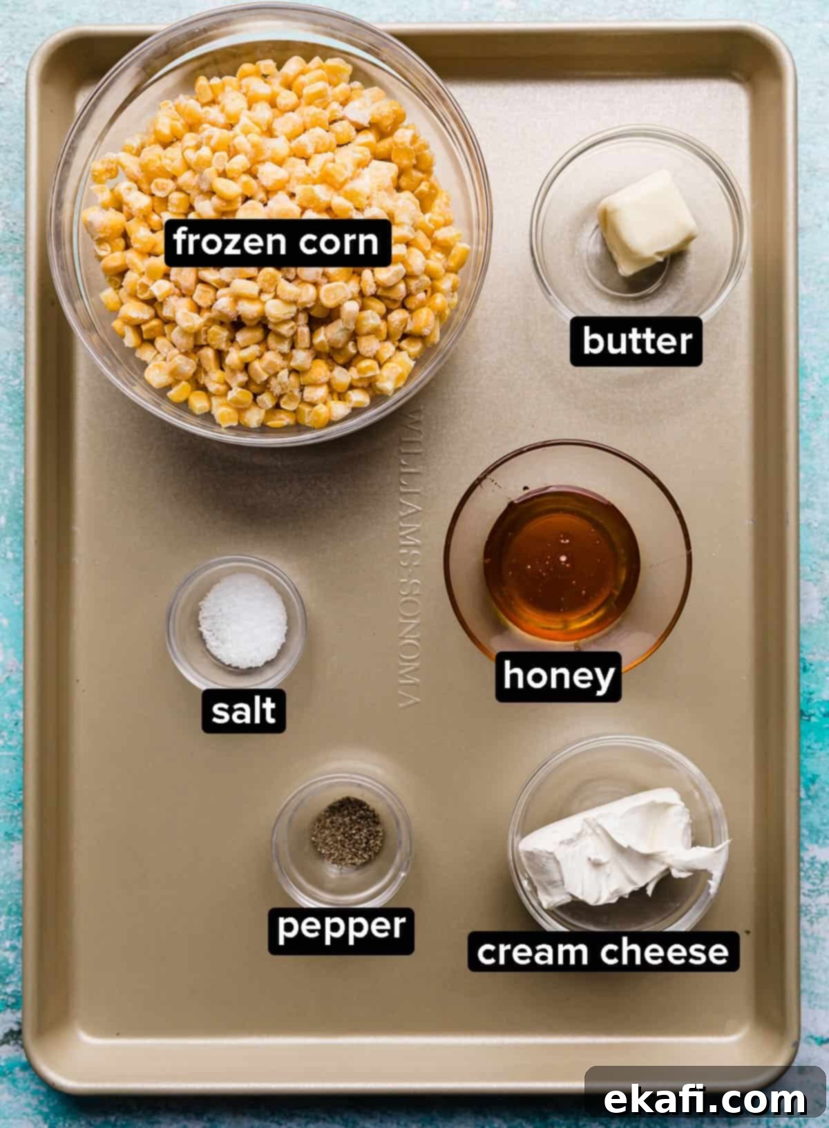 Golden Honey Butter Skillet Corn 3 A bronze baking sheet with glass bowls filled with frozen corn, honey, butter, cream cheese, and salt and pepper.