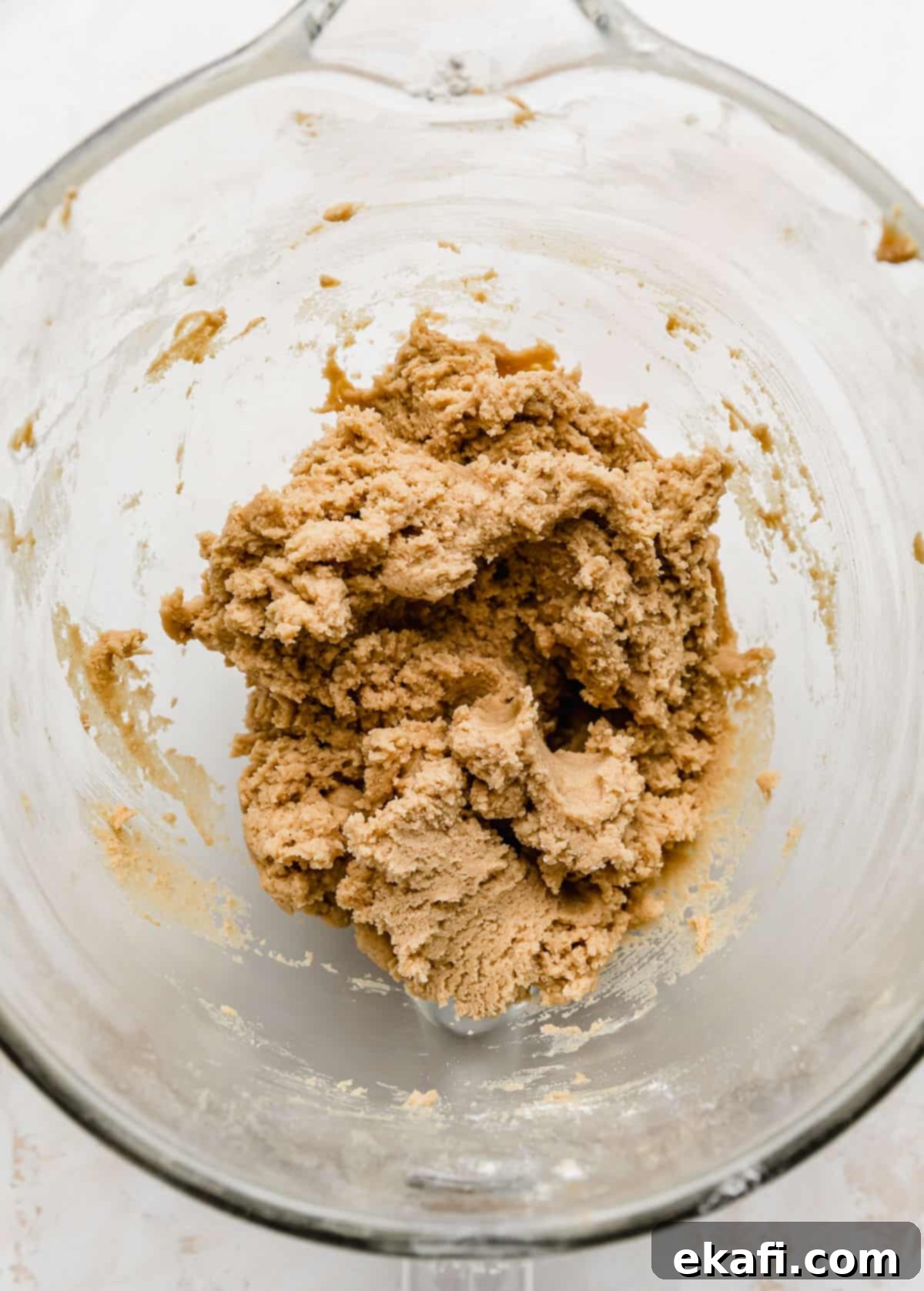 Crumbl Κλασικά Μπισκότα Φυστικοβούτυρου 4 Μια κοντινή φωτογραφία ζύμης για Κλασικά Κουλουράκια Φυστικοβούτυρου Crumbl σε ένα γυάλινο μπολ.