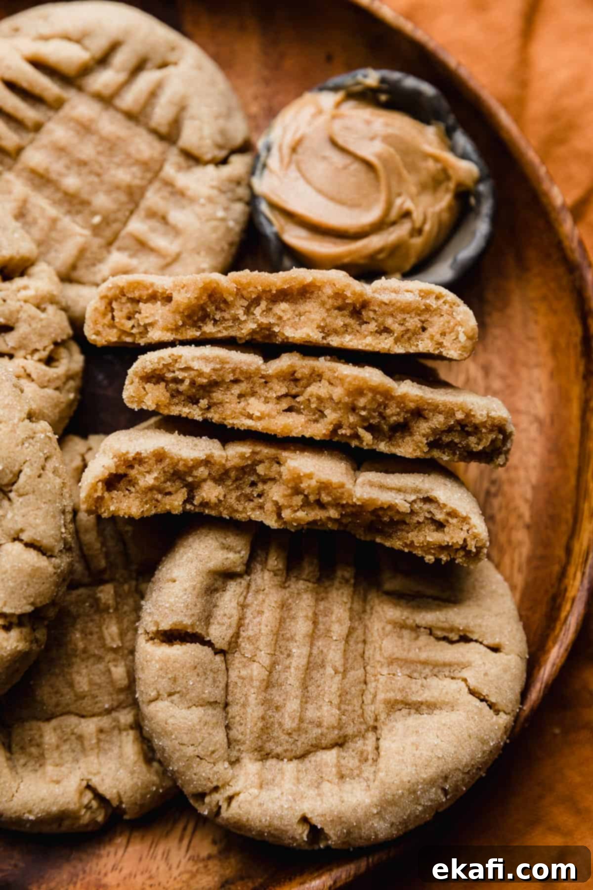Crumbl Κλασικά Μπισκότα Φυστικοβούτυρου 9 Κλασικά κουλουράκια φυστικοβούτυρου κομμένα στη μέση σε ένα πορτοκαλί πιάτο.