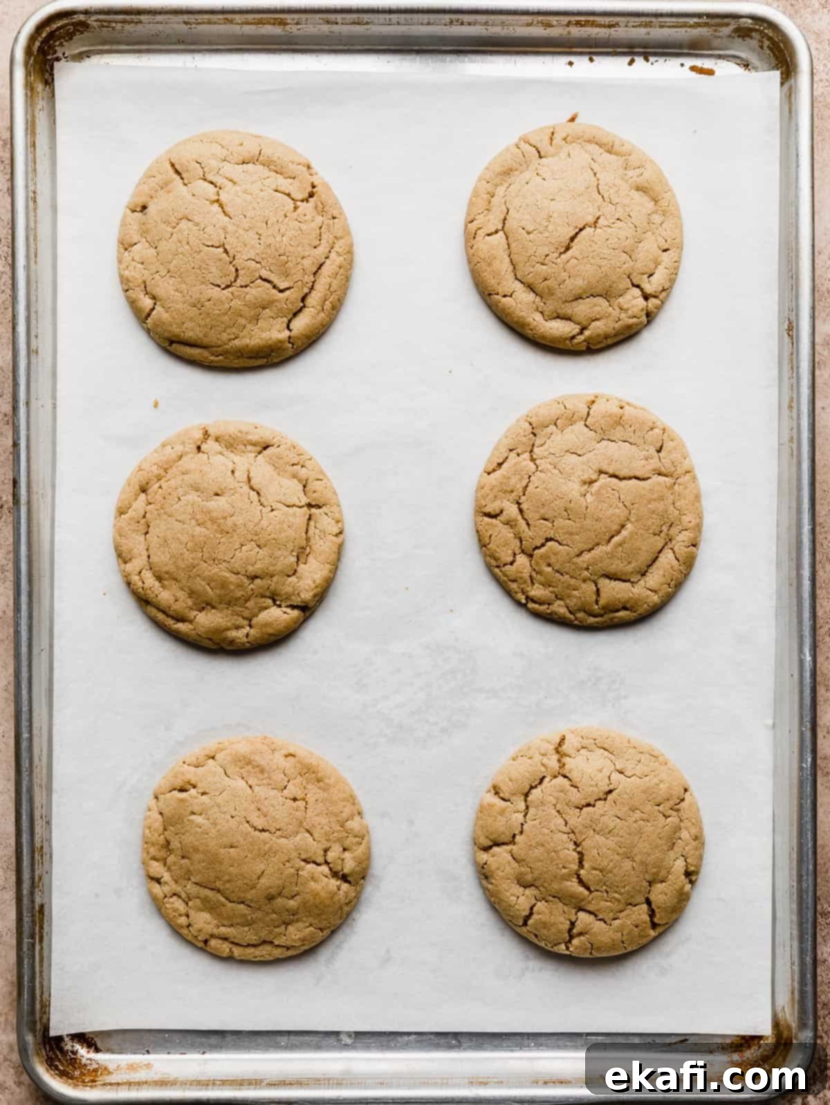 Decadent Peanut Butter Cup Cookies 4 Six baked peanut butter cookies on a white parchment lined baking sheet.