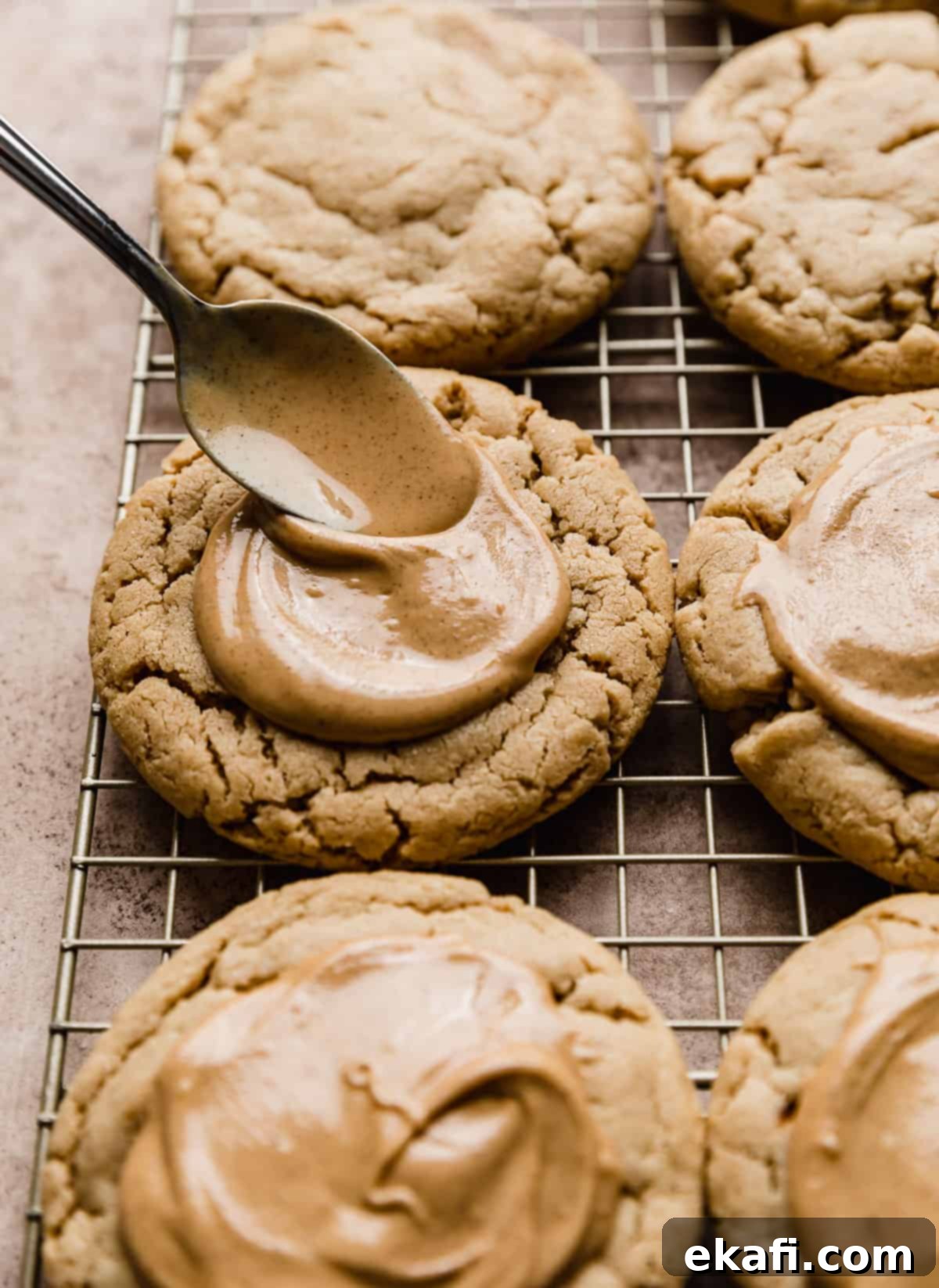 Decadent Peanut Butter Cup Cookies 6 A spoon spreading melted peanut butter on top of a peanut butter cookie.