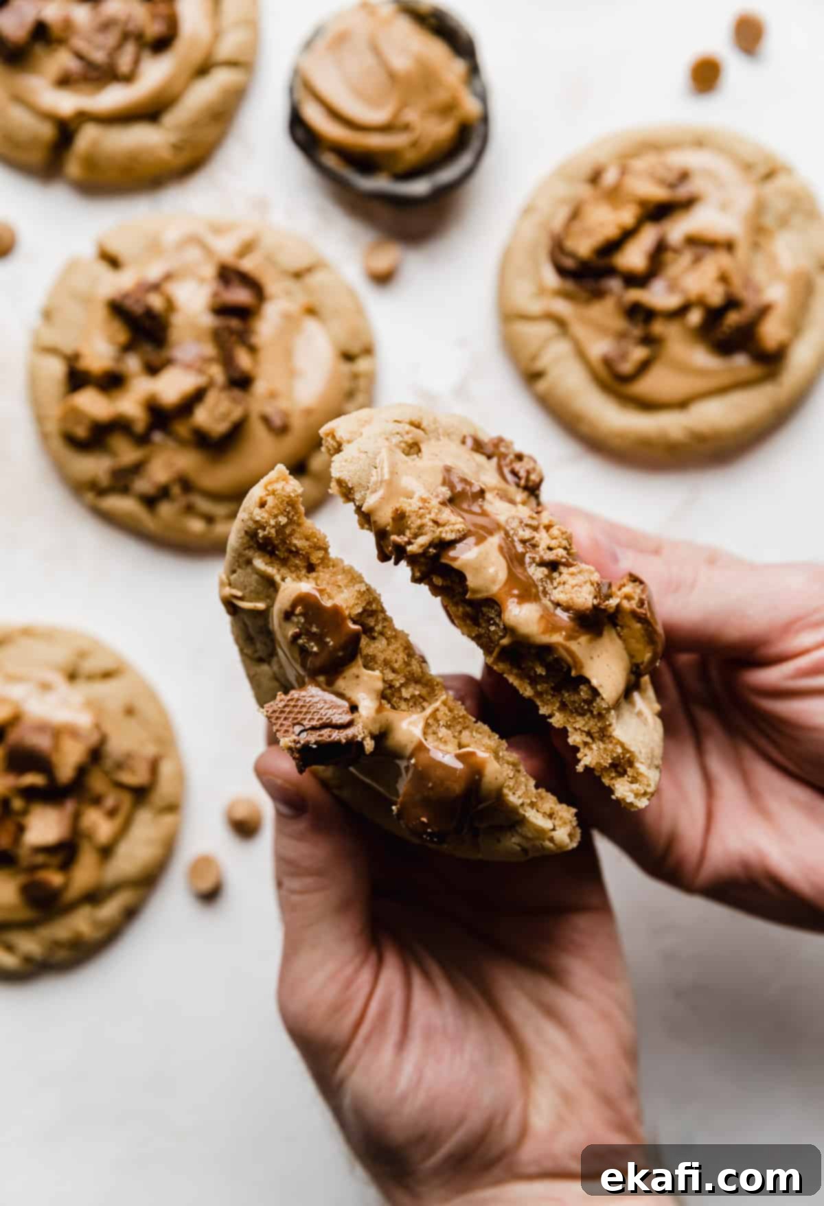 Decadent Peanut Butter Cup Cookies 10 A pair of hands breaking a copycat Crumbl Peanut Butter Cup Cookie in half.