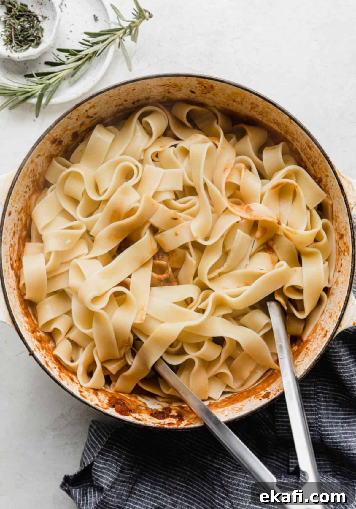 Hearty Shredded Beef Ragu 14 Pappardelle noodles in a white pot against a white background.