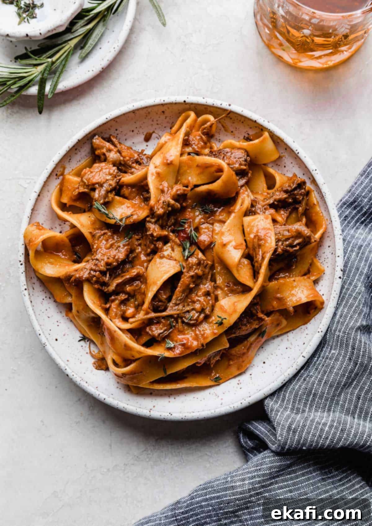 Hearty Shredded Beef Ragu 16 A white plate with homemade beef Ragu with pappardelle noodles on a white background.