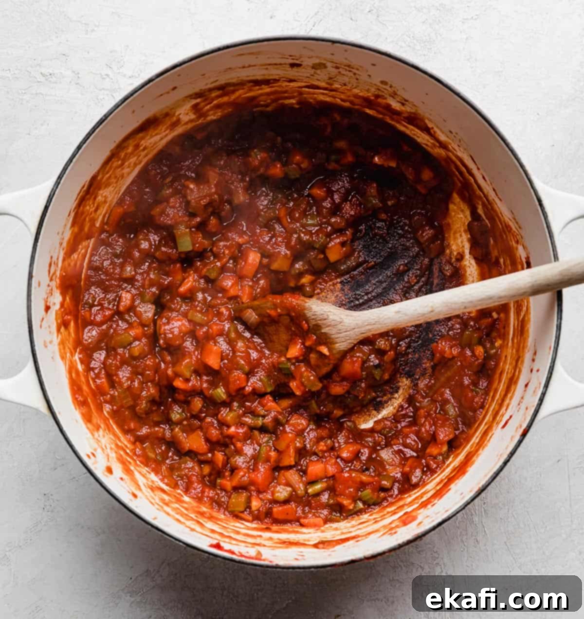 Hearty Shredded Beef Ragu 6 A beef Ragu soffritto and a tomato paste sauce in a large white pot.