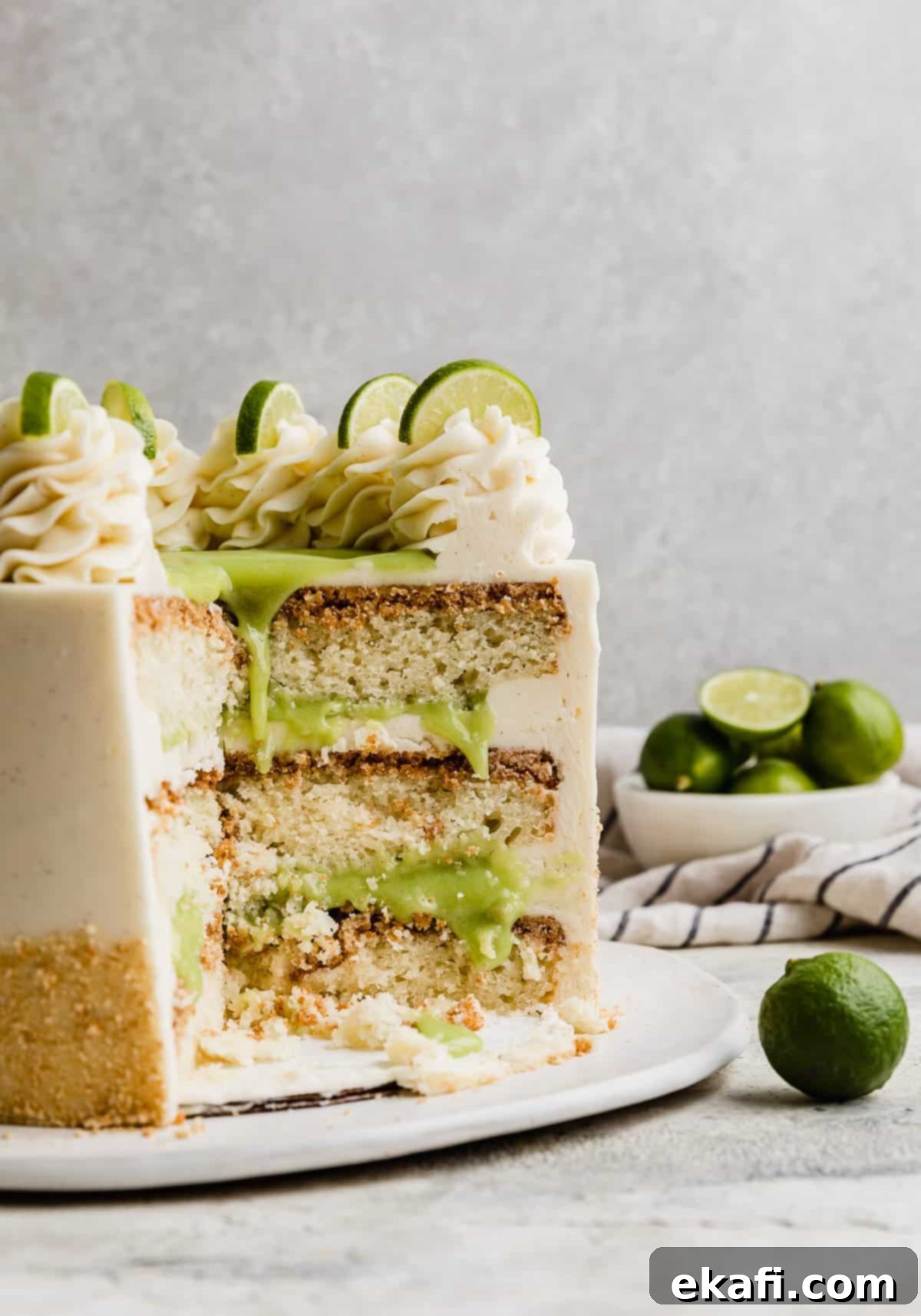 Key Lime Dream Cake 2 A Key Lime Cake Recipe cut, exposing the three slices of lime cake baked on graham cracker crusts and filled with a light green key lime curd and white frosting.