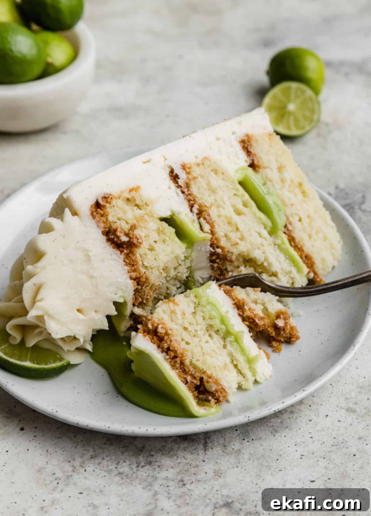 Key Lime Dream Cake 3 A three cake layered Key Lime Cake slice on a white plate.