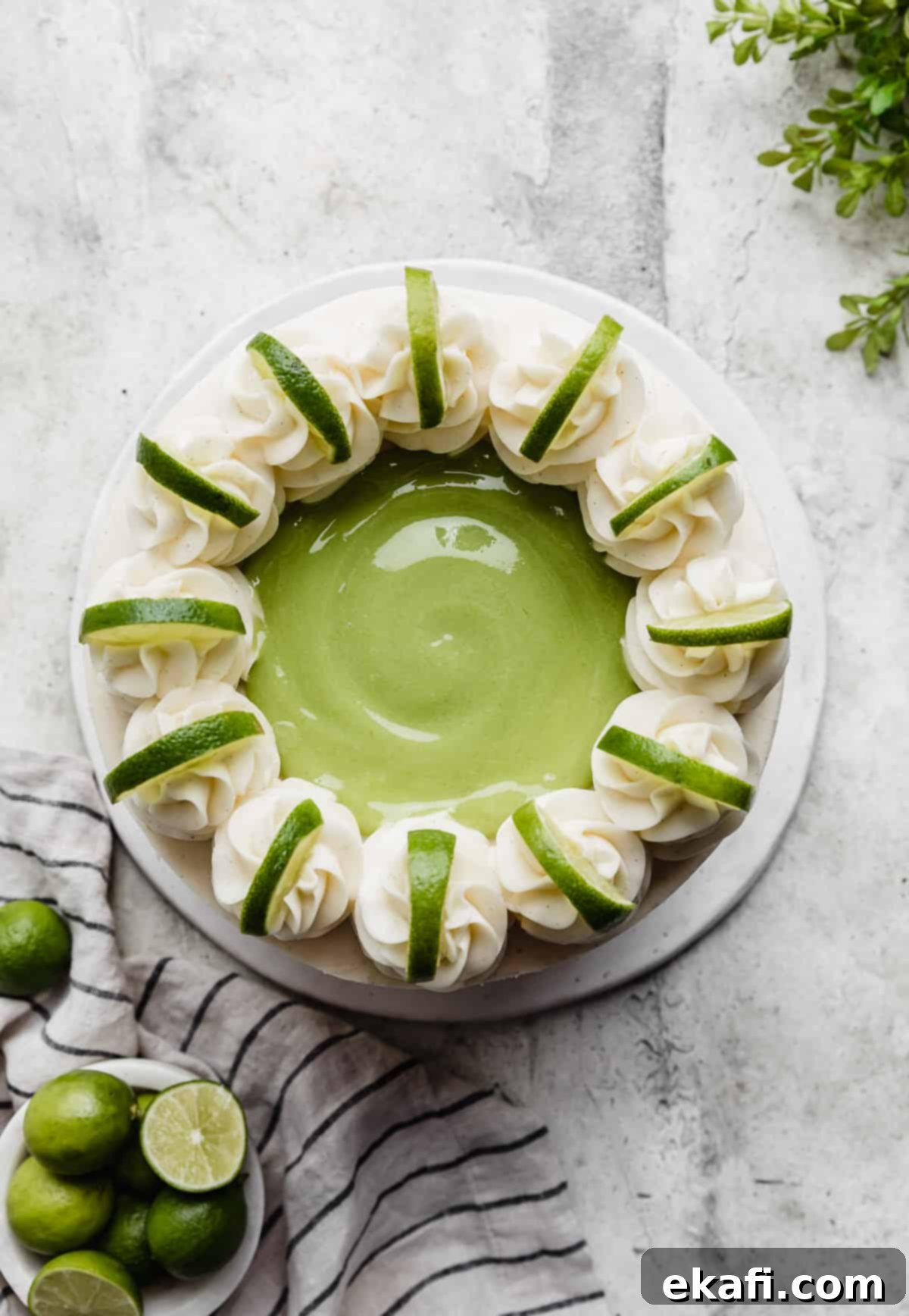 Key Lime Dream Cake 8 Overhead photo of a Key Lime Cake topped with lime curd, frosting swirls and lime slices on each swirl.