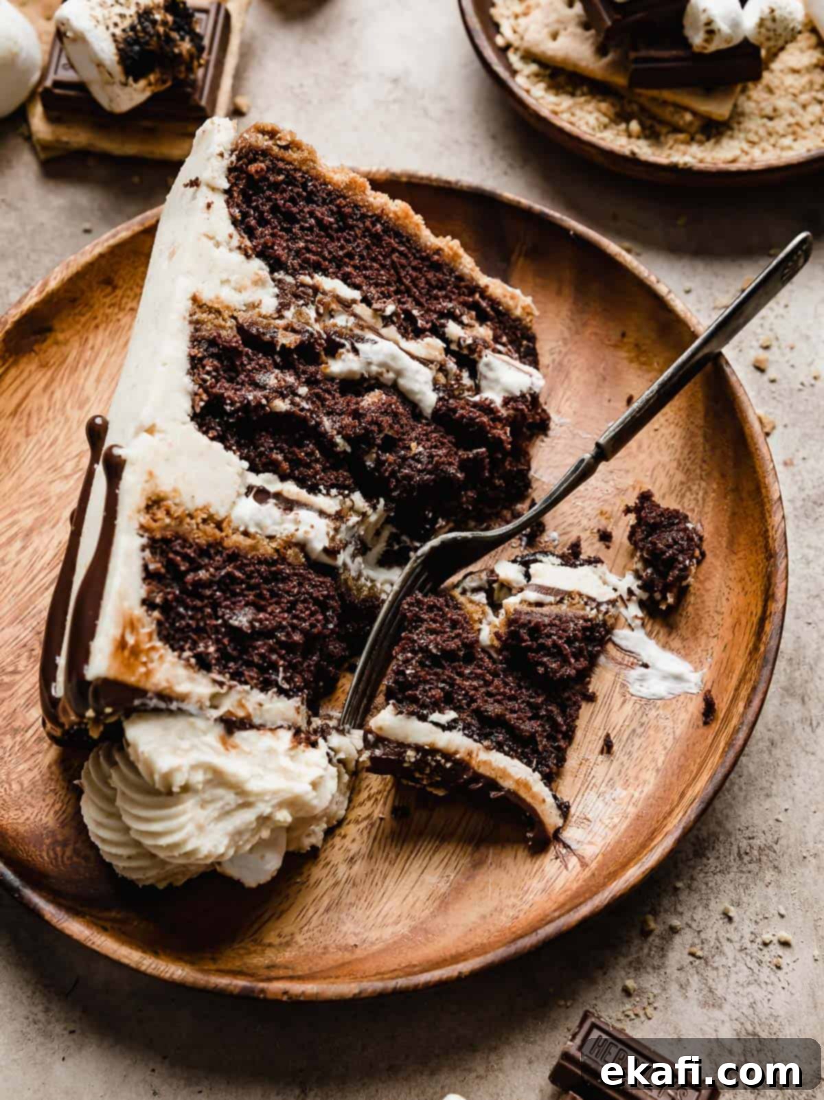 S'mores Cake 3 A slice of S'mores Cake on a brown wooden plate on a beige background.