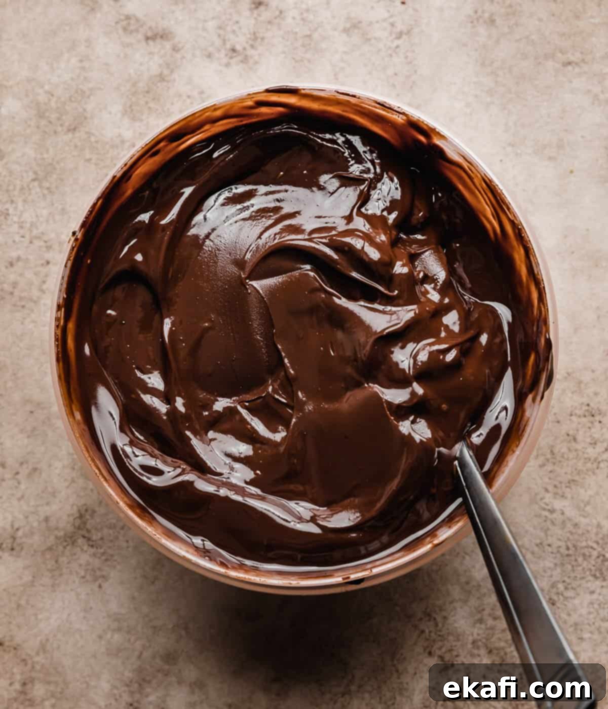 S'mores Cake 5 Chocolate ganache in a bowl on a beige background, to be used as a filling for a s'mores layer cake.