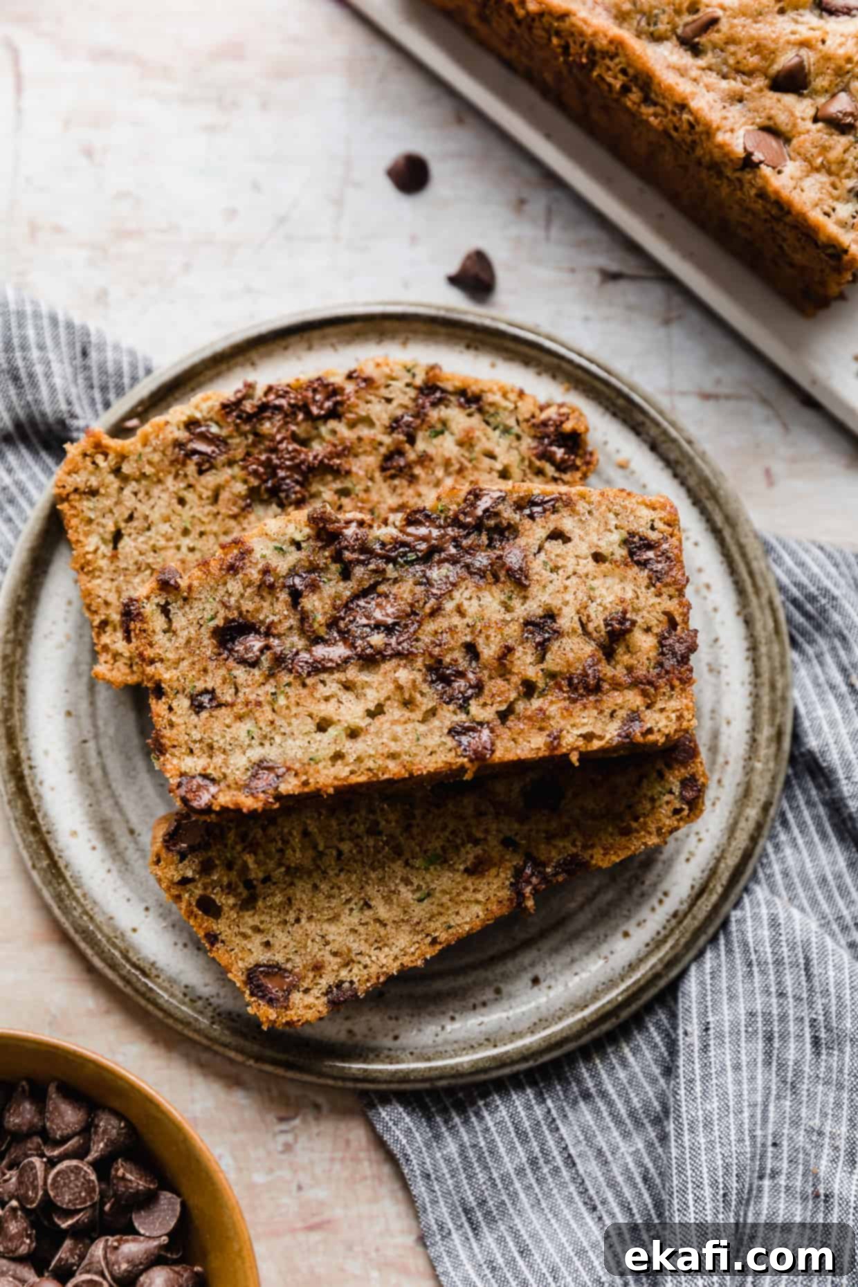 Decadent Chocolate Chip Zucchini Loaf 2 A perfectly sliced piece of moist Chocolate Chip Zucchini Bread on a gray plate, showcasing the chocolate chips and green flecks of zucchini.