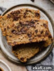 Decadent Chocolate Chip Zucchini Loaf 14 A slice of Chocolate Chip Zucchini Bread on a gray plate.