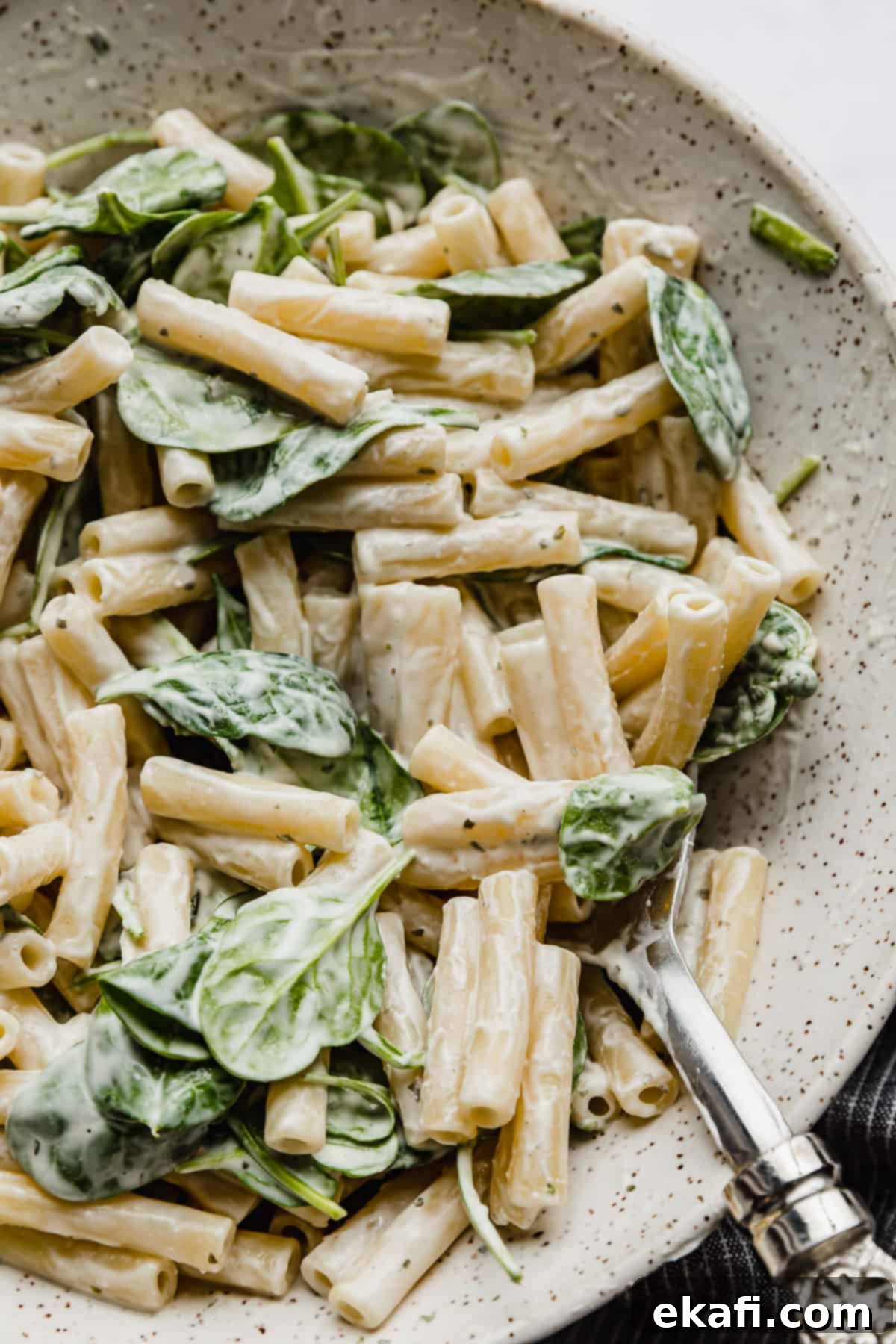 Creamy Boursin Pasta 2 Creamy Boursin pasta recipe tossed with spinach in a serving bowl with a serving spoon in the bowl.