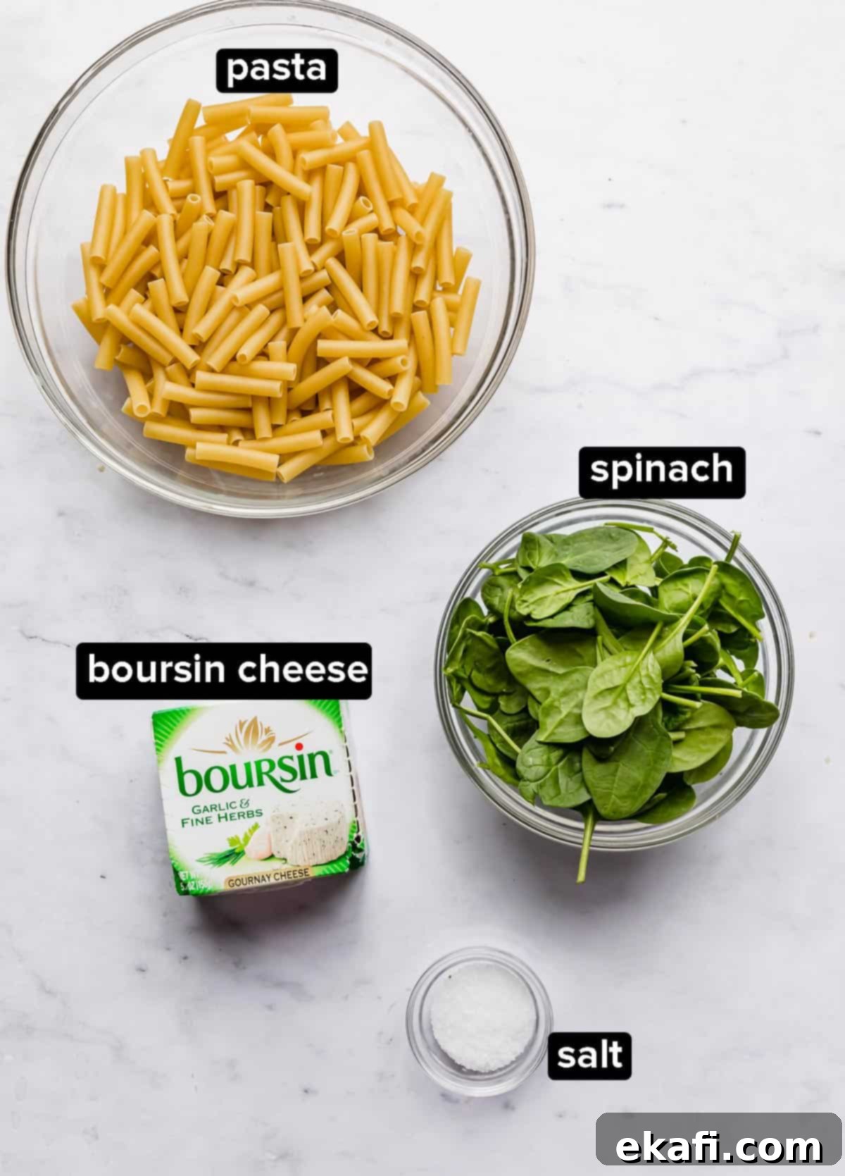 Creamy Boursin Pasta 3 Boursin Pasta recipe ingredients on a white marble background: spinach, pasta, boursin cheese, salt.