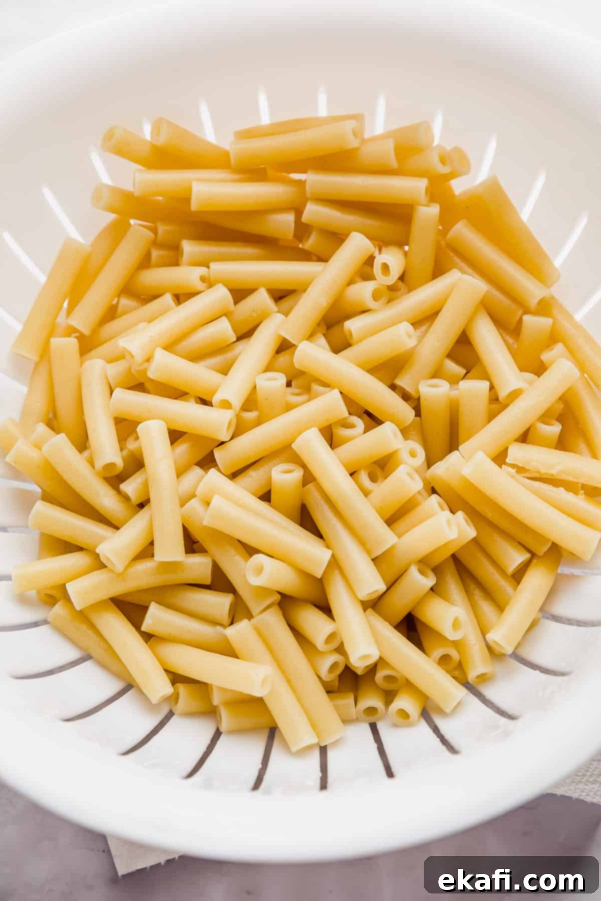 Creamy Boursin Pasta 4 Cooked ziti pasta noodles in a white colander.