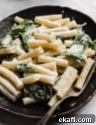Creamy Boursin Pasta 8 A black plate with creamy Boursin Pasta tossed with spinach.