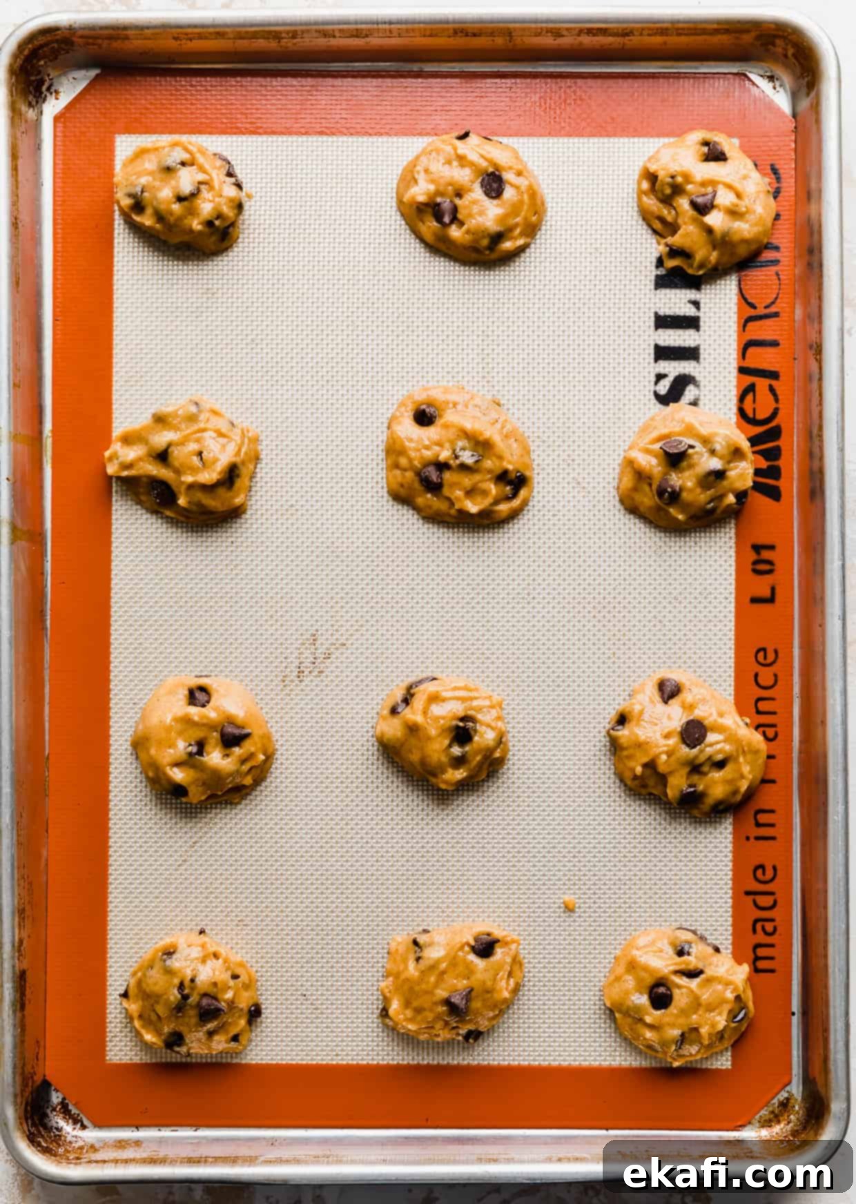 Spiced Pumpkin Chocolate Chip Delights 14 Perfectly portioned pumpkin chocolate chip cookie dough balls, neatly arranged on a baking sheet, ready for the oven.