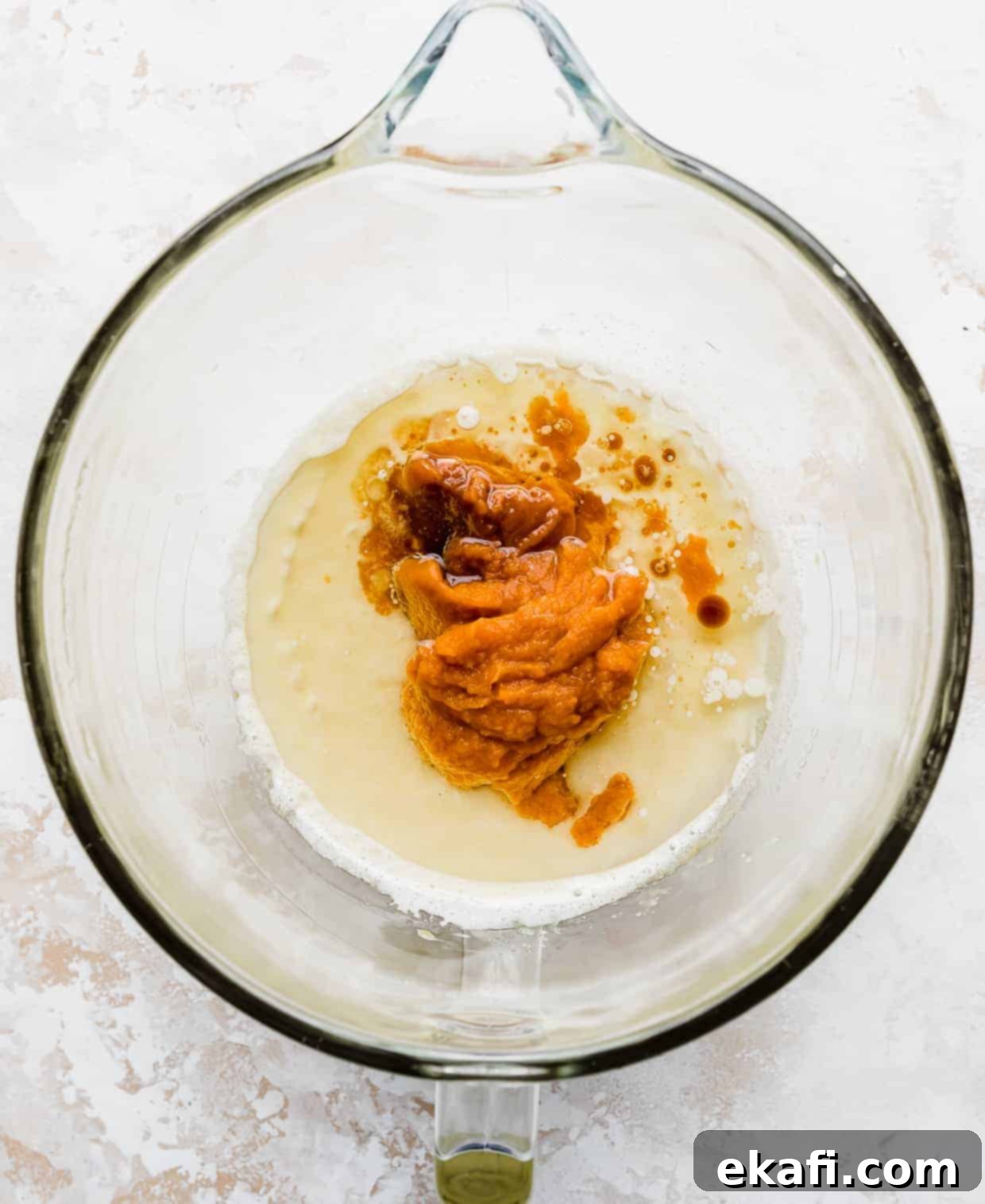 Spiced Pumpkin Chocolate Chip Delights 8 Vibrant orange pumpkin puree carefully added to a glass mixing bowl with other wet ingredients, essential for moist pumpkin chocolate chip cookies.