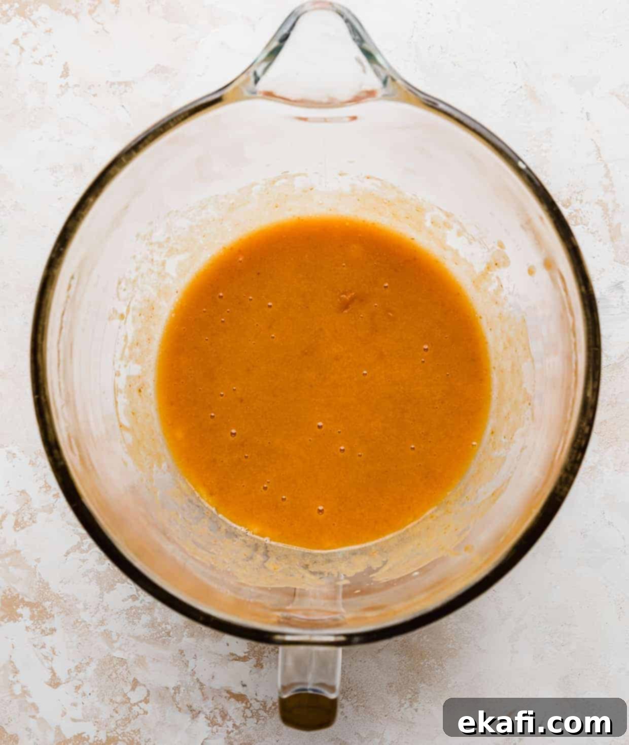 Spiced Pumpkin Chocolate Chip Delights 9 A smooth, orange liquid mixture in a glass mixing bowl, perfectly blended for crafting delightful Libby's Pumpkin Chocolate Chip Cookies.