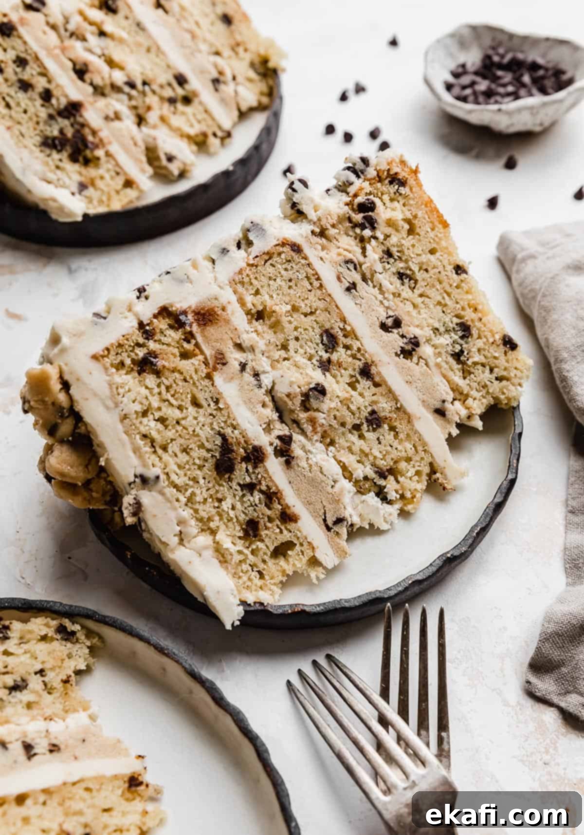 The Ultimate Cookie Dough Dream Cake 12 A stunning slice of Cookie Dough Cake, revealing perfectly layered brown butter cake and edible cookie dough, on a black-rimmed white plate.