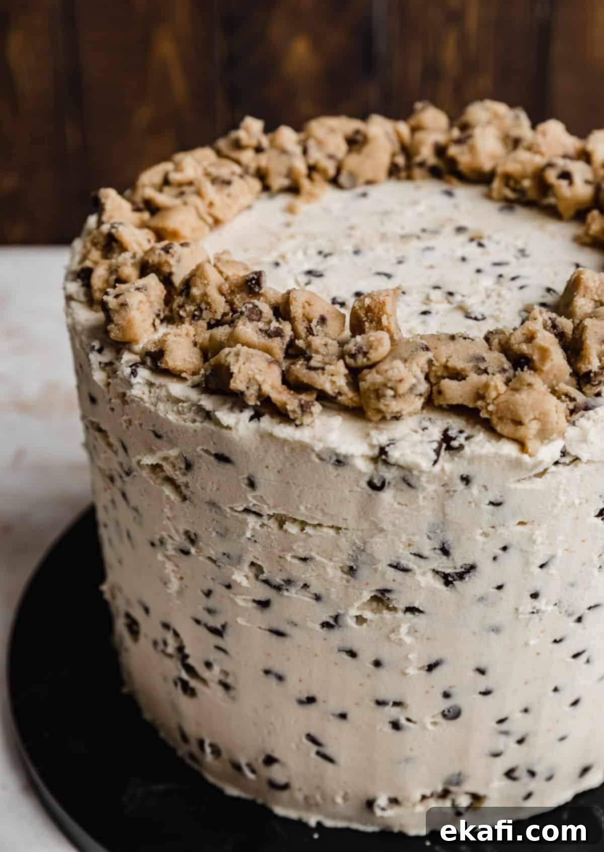 The Ultimate Cookie Dough Dream Cake 3 A tall, layered Brown Butter Cookie Dough Cake, frosted with a light buttercream studded with mini chocolate chips and topped with edible cookie dough crumbles.