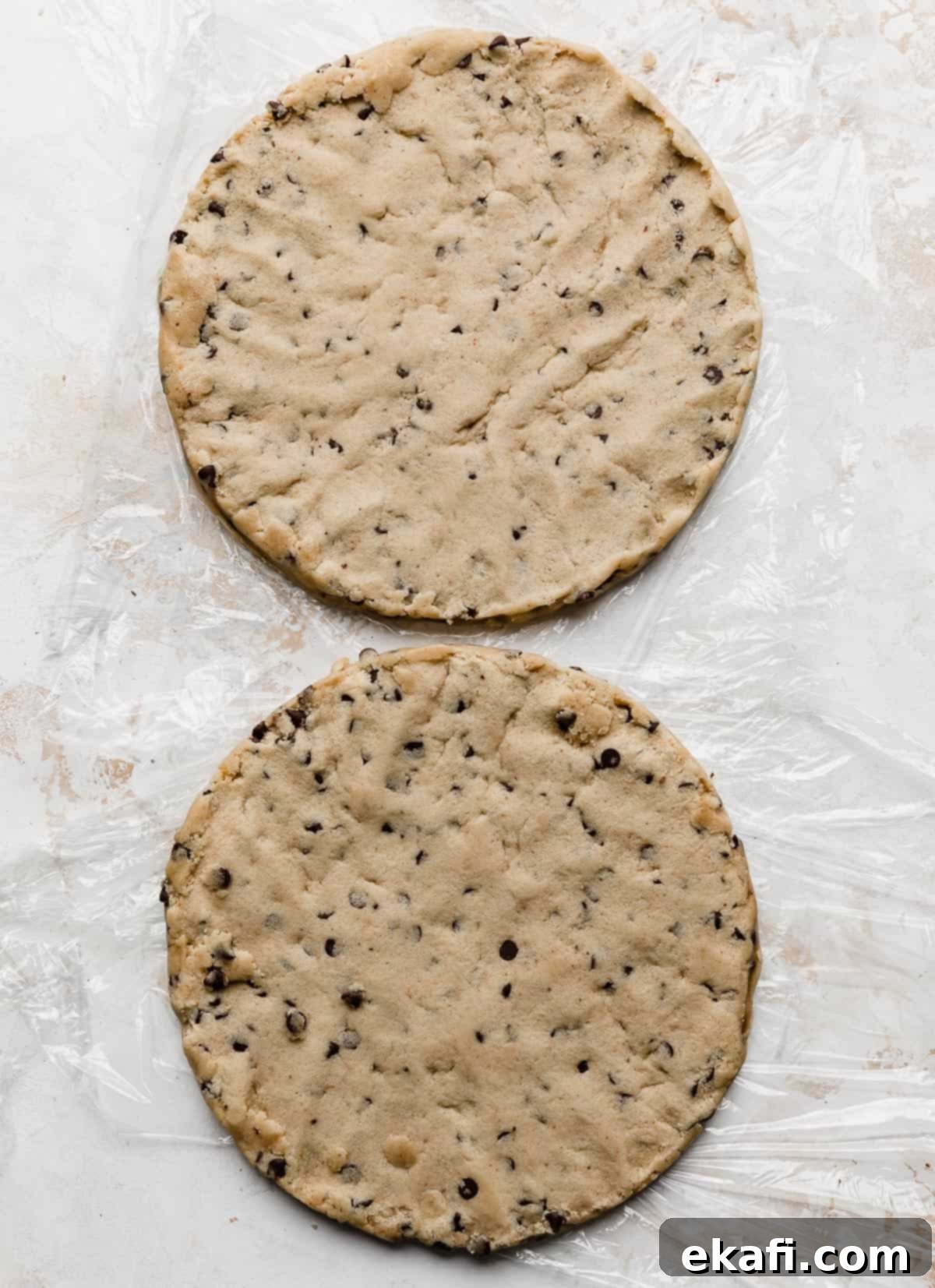 The Ultimate Cookie Dough Dream Cake 5 Two perfectly round disks of edible cookie dough, prepared to be layered into the cake, resting on a white surface.