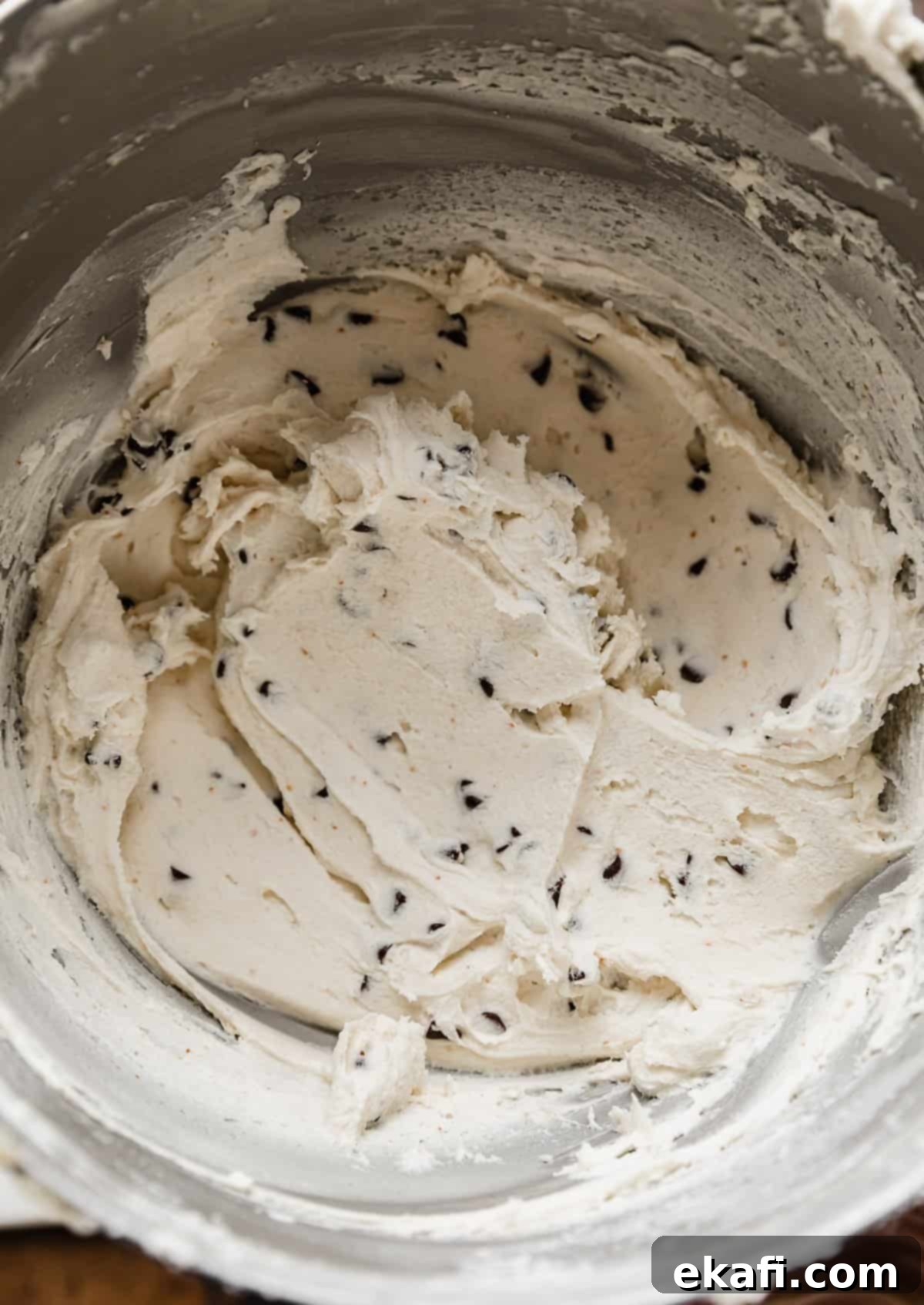 The Ultimate Cookie Dough Dream Cake 9 A close-up of white buttercream frosting, perfectly mixed with mini chocolate chips, ready for the final cake decoration.