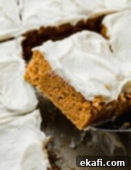 Golden Pumpkin Spice Bars 10 A single square of Libby's Pumpkin Bar with cream cheese frosting, carefully balanced on a metal spatula, ready to be served.