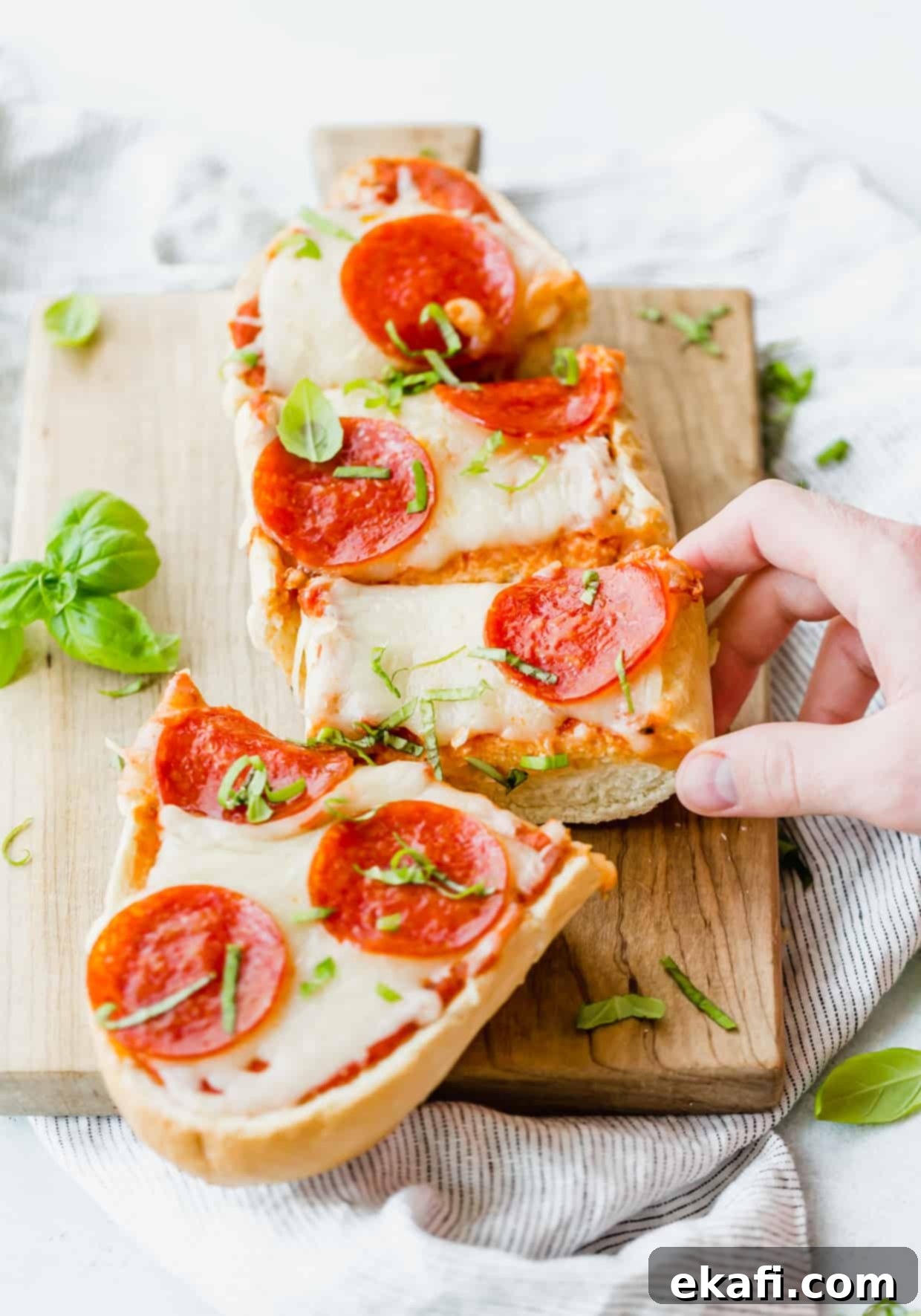 French Bread Pizza 12 French bread pizza on a cutting board, topped with pepperoni and fresh basil.