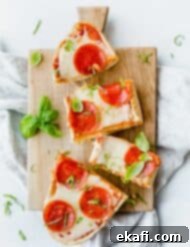French Bread Pizza 13 Overhead view of French Bread Pizza with pepperoni on top and a basil garnish.