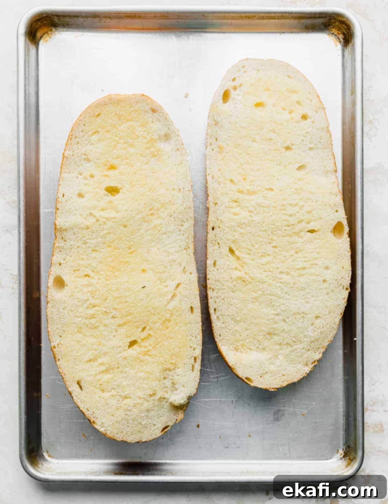 French Bread Pizza 5 Two open faced slices of French bread on a baking sheet.