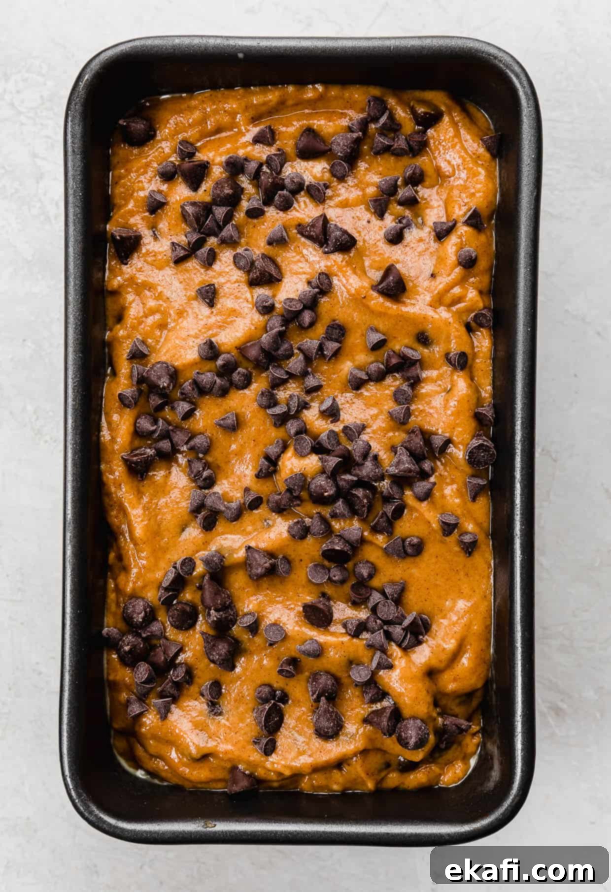 Spiced Chocolate Chip Pumpkin Loaf 6 Unbaked Pumpkin Chocolate Chip Bread in a loaf pan topped with mini chocolate chips and semi-sweet chocolate chips, ready for the oven.