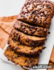 Spiced Chocolate Chip Pumpkin Loaf 10 A sliced Pumpkin Chocolate Chip Bread on a white plate, highlighting its moist interior and chocolate chips.