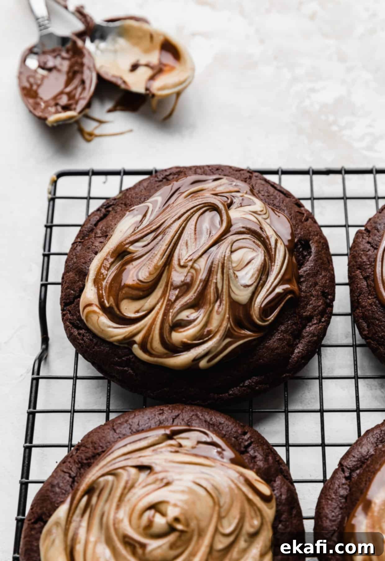 Μπισκότα με φυστικοβούτυρο και καφέ brownie Crumbl 12 Σοκολάτα και φυστικοβούτυρο ανακατεμένα πάνω από ένα μπισκότο μπράουνι σε μια σχάρα.